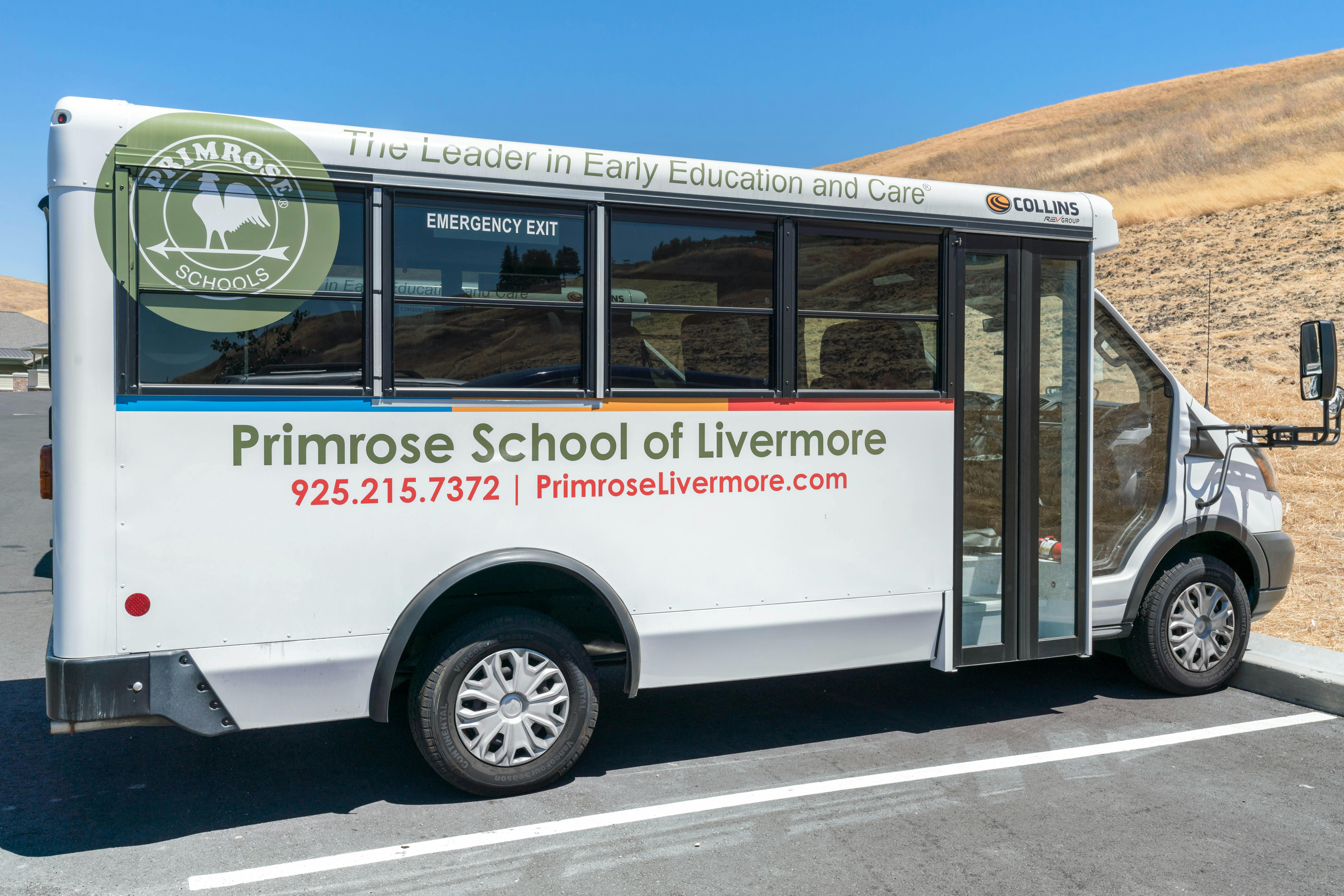 White school bus for Primrose School of Livermore parked on asphalt