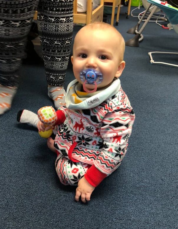 Child with pacifier sitting on a carpeted floor