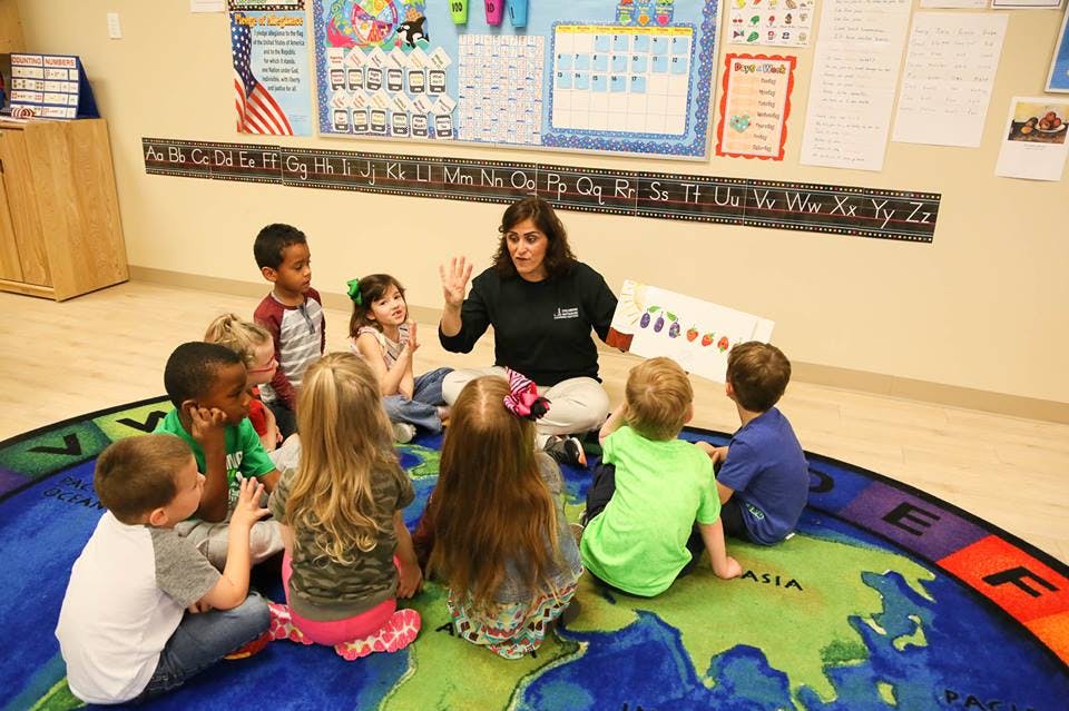 Person reading to a group of children sitting on a rug