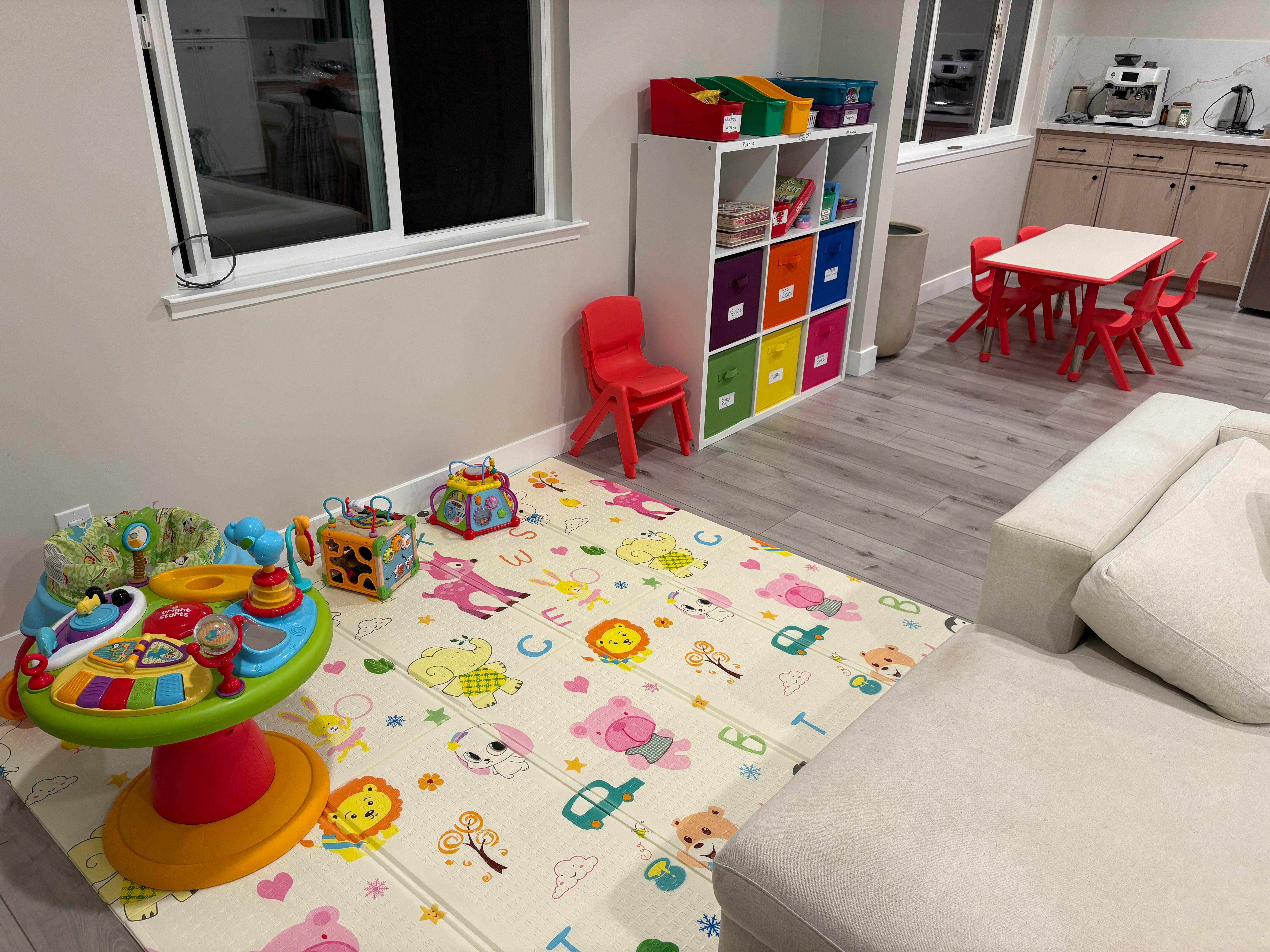 Playroom with a patterned floor mat, activity toys, and a storage unit