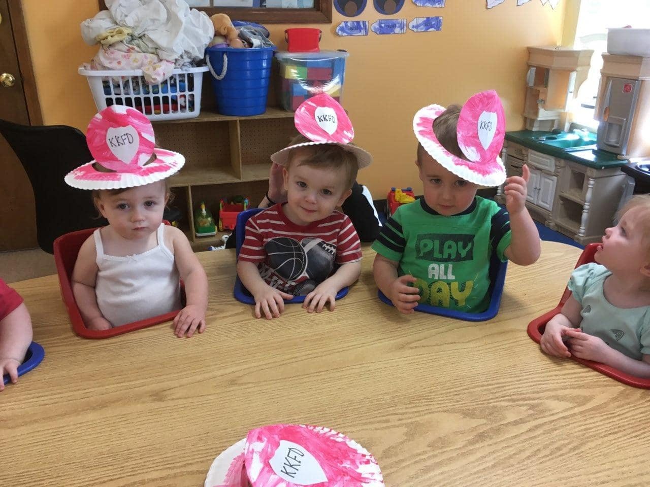 Children wearing paper hats sitting at a table