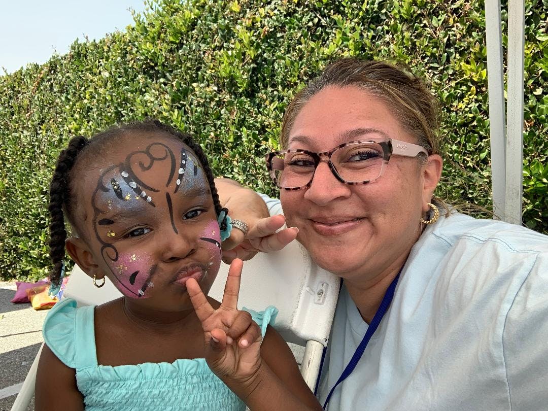 Adult and child with face paint making peace signs