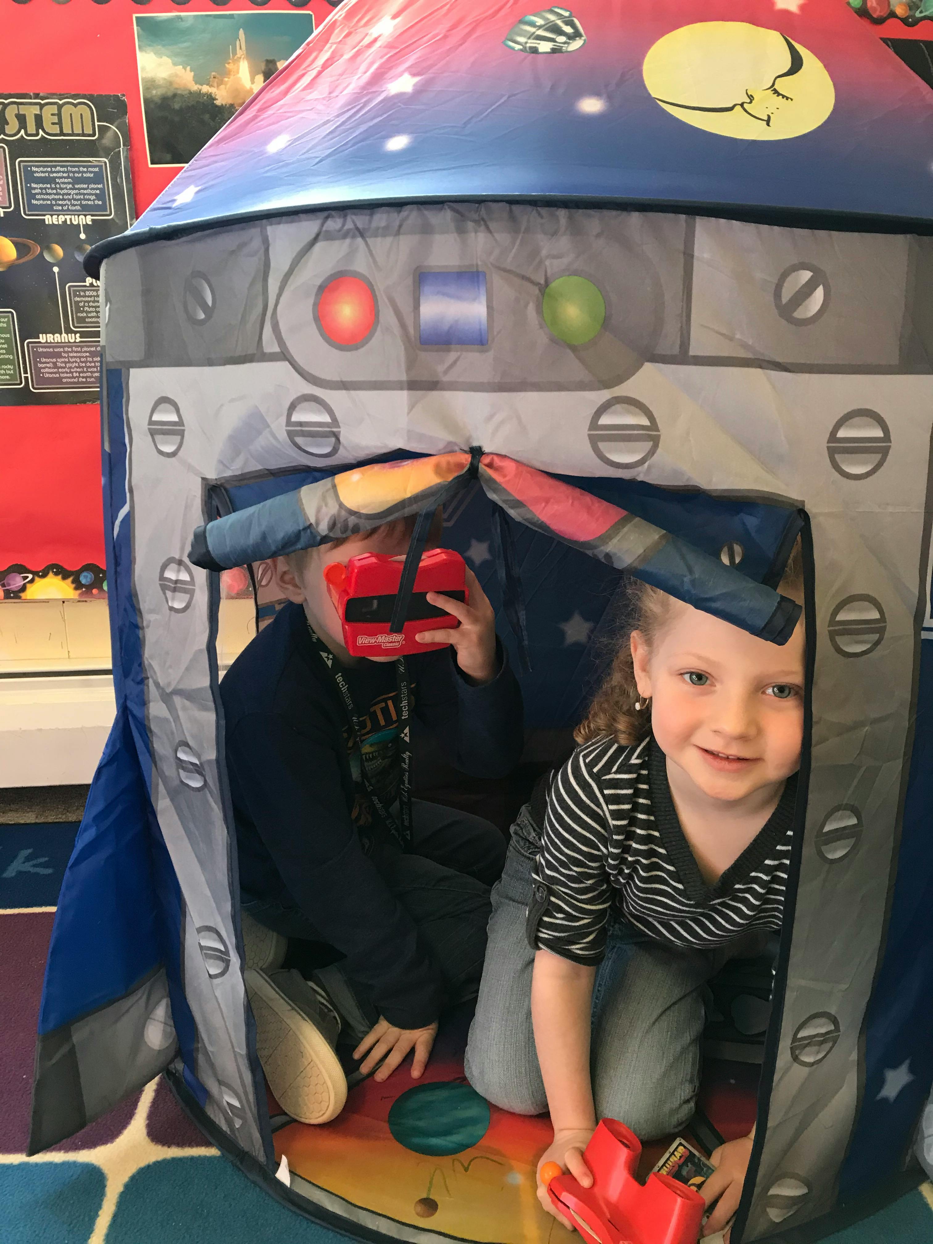 Two children playing inside a rocket ship play tent