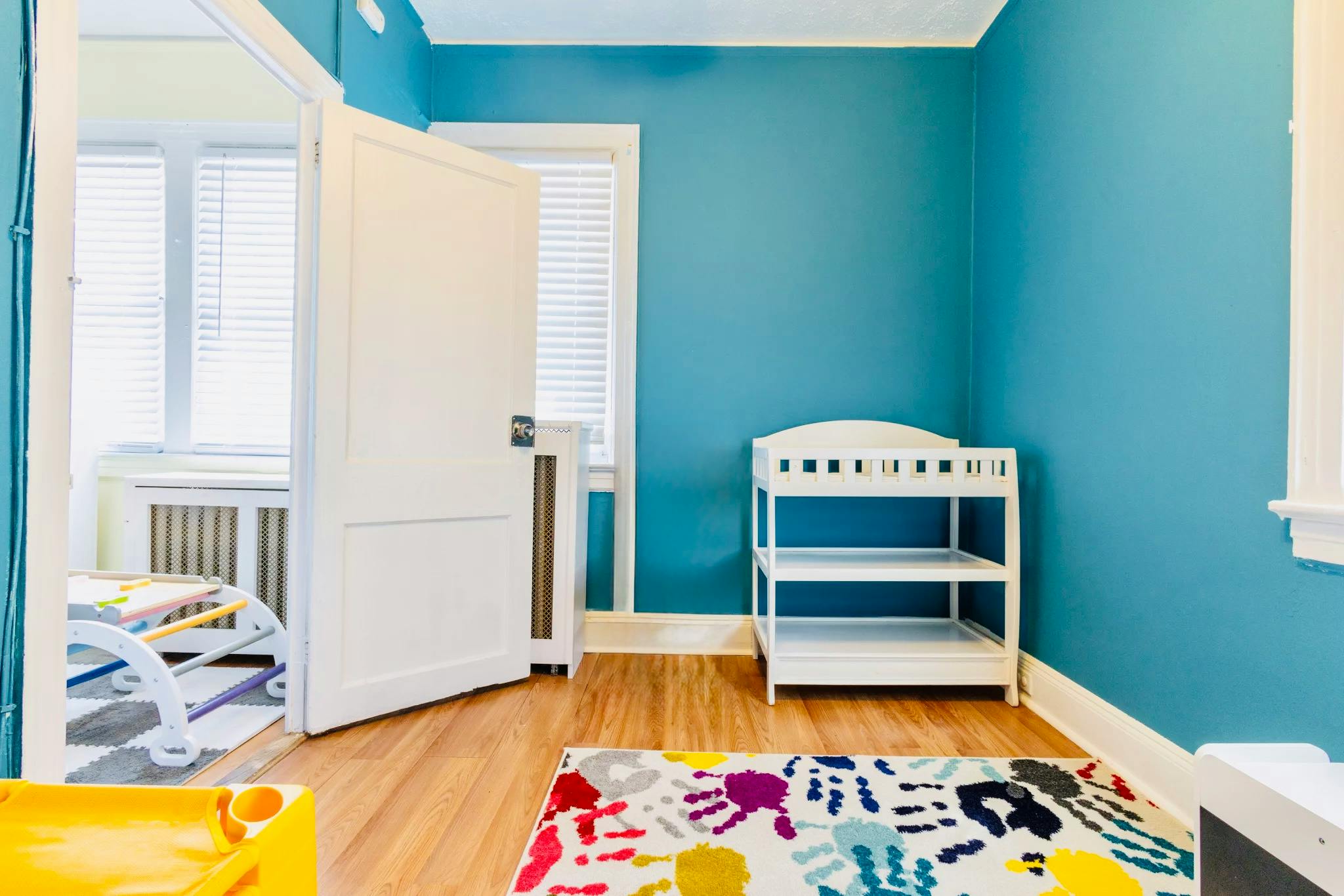 A changing table in a nursery with a colorful rug