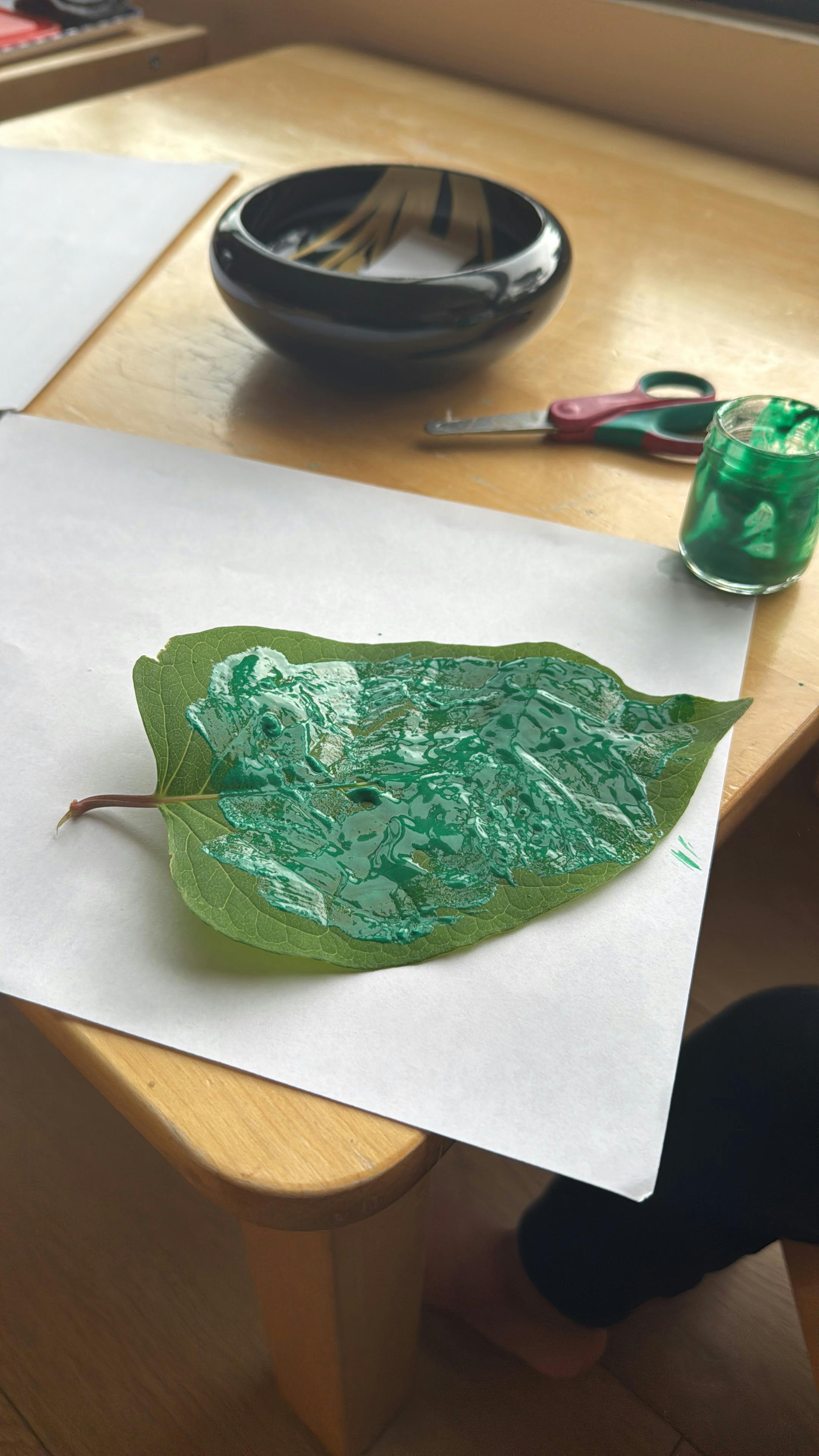 Green leaf with green paint on a white paper