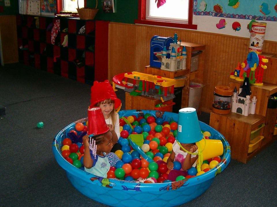 Children playing in a ball pit with buckets on their heads