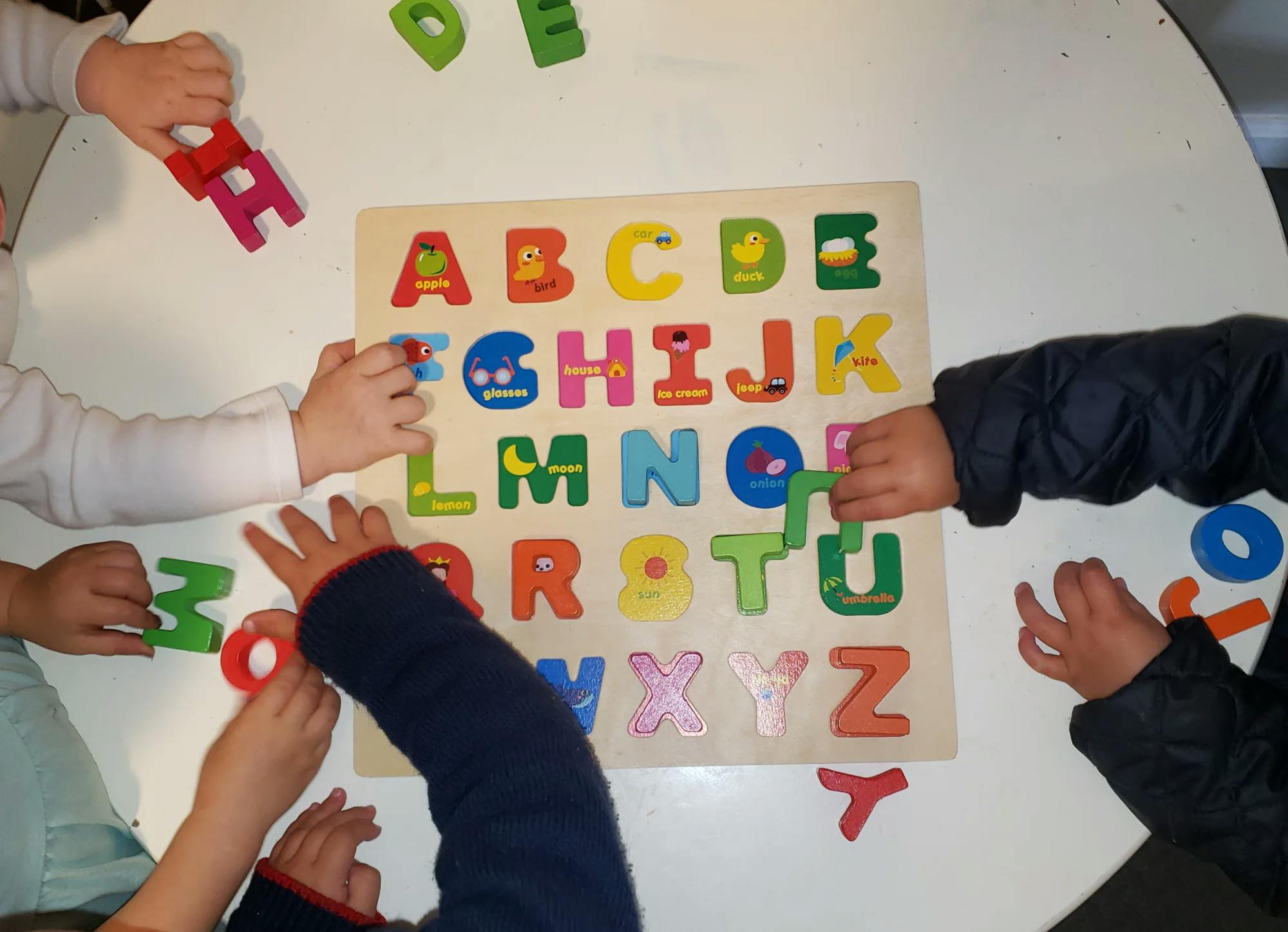 Children playing with an alphabet letter puzzle