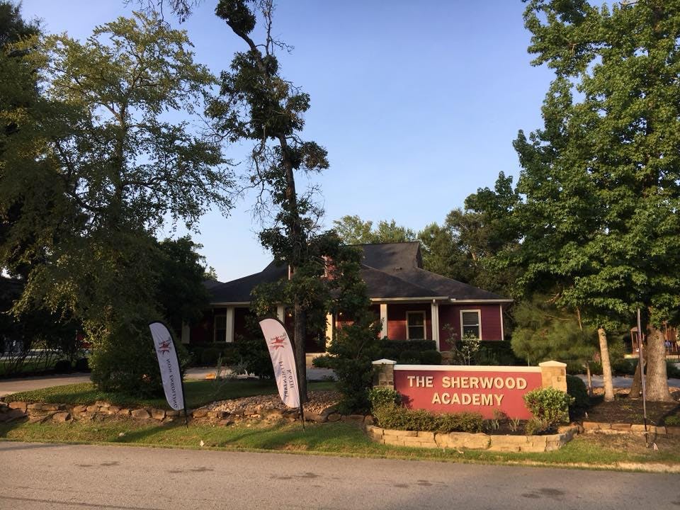The Sherwood Academy sign in front of a building surrounded by trees