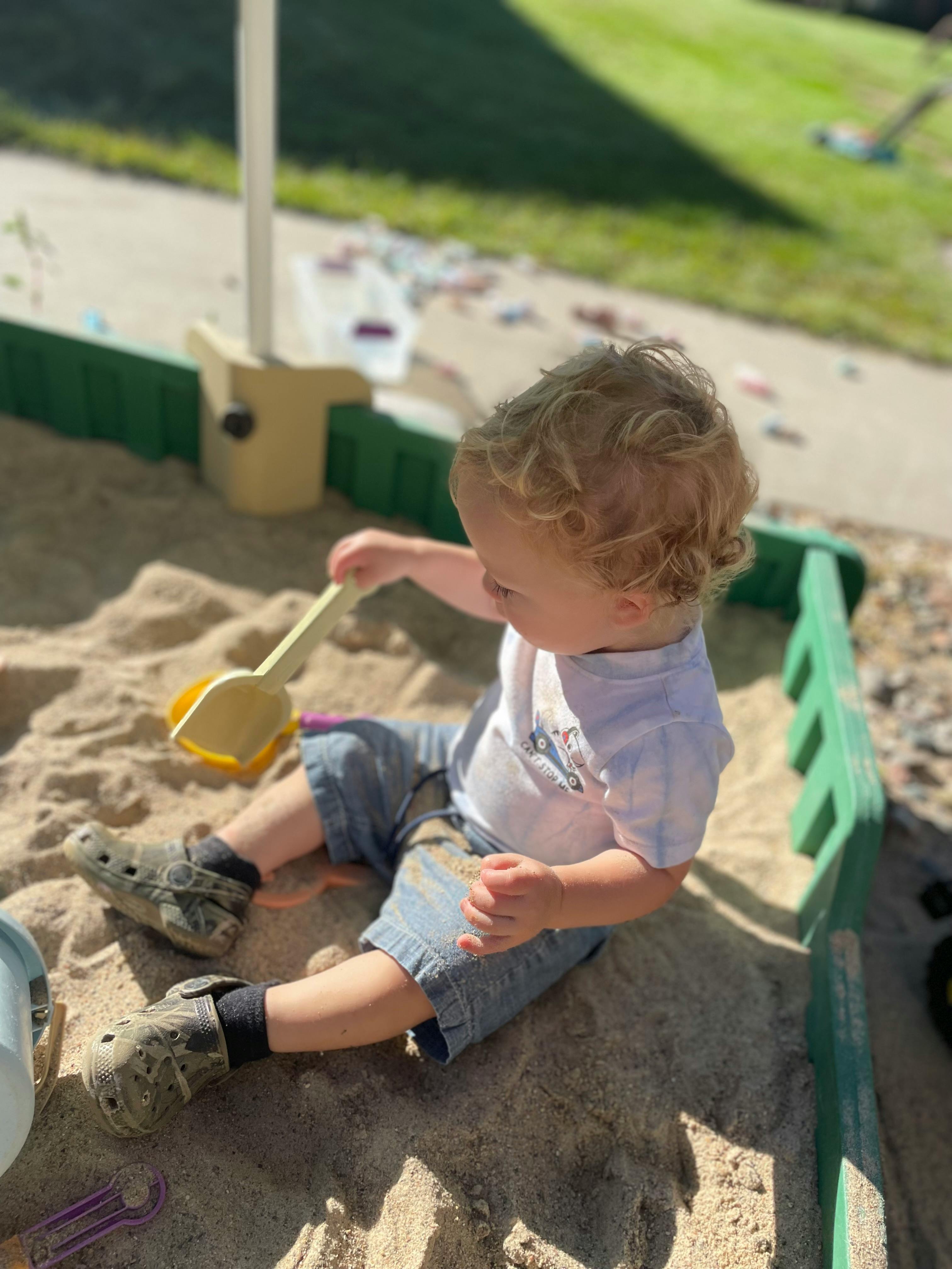 Child playing in a sandbox with a shovel