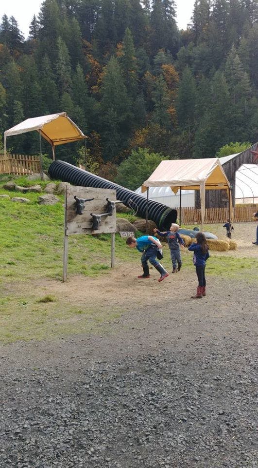 Children playing near a large black tube slide and a wooden game
