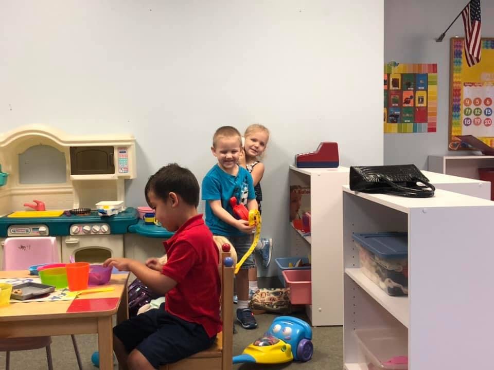 Three children playing in a classroom