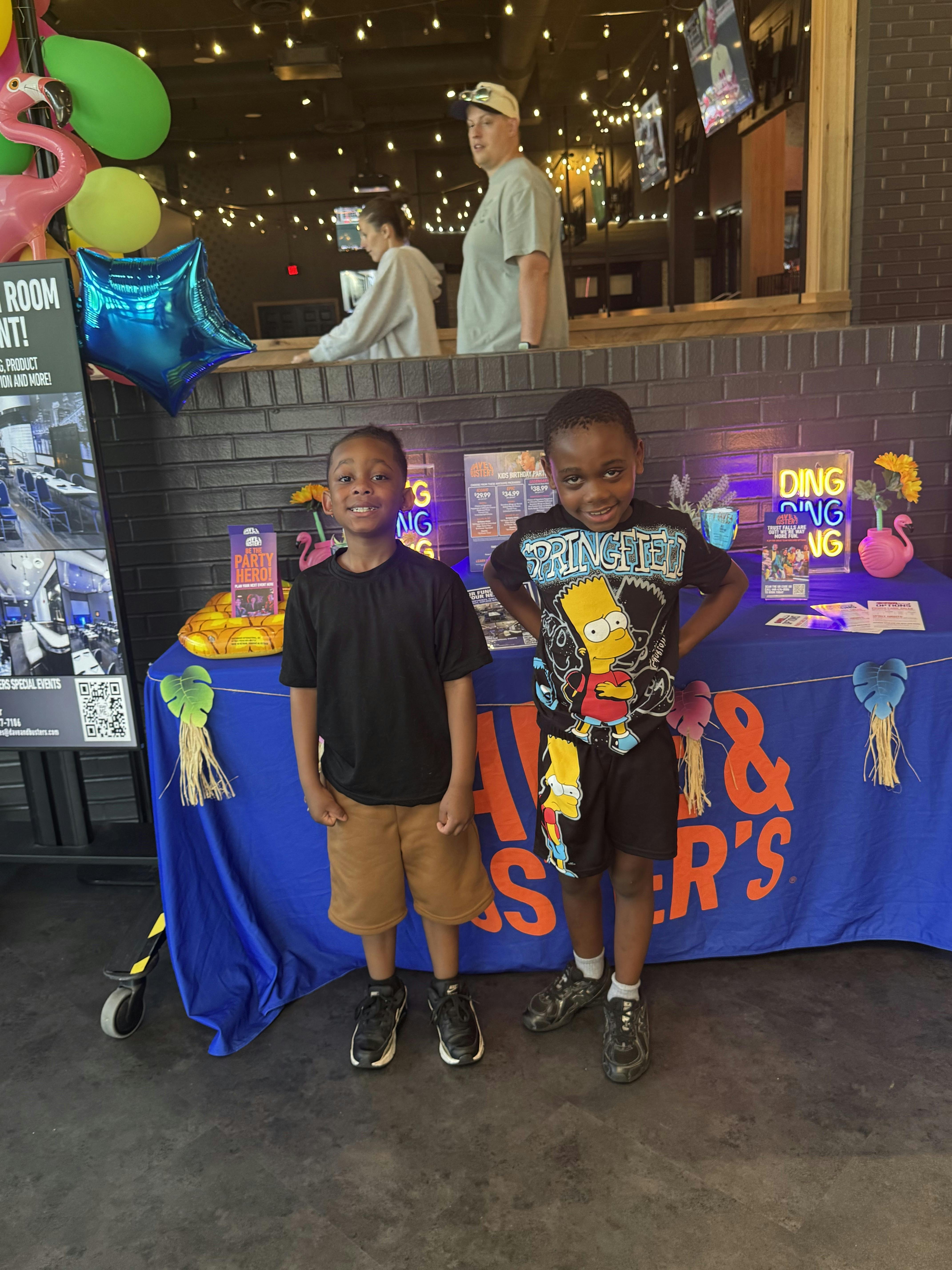 Two children standing in front of a blue table with decorations