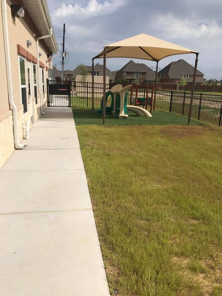 Playground with a slide under a canopy next to a building