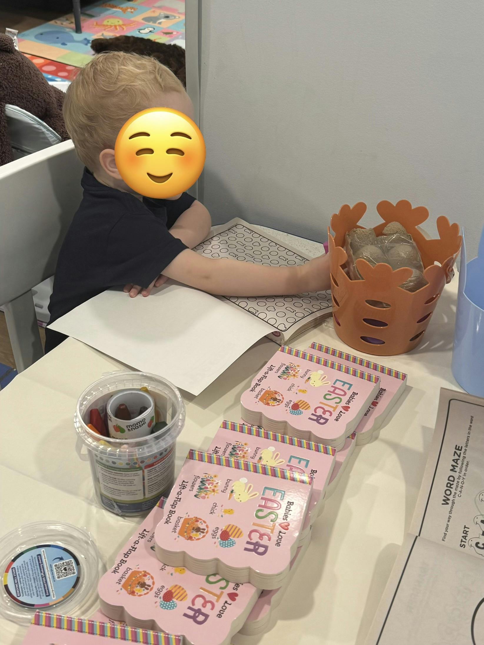Child coloring at a table with Easter-themed books and craft supplies