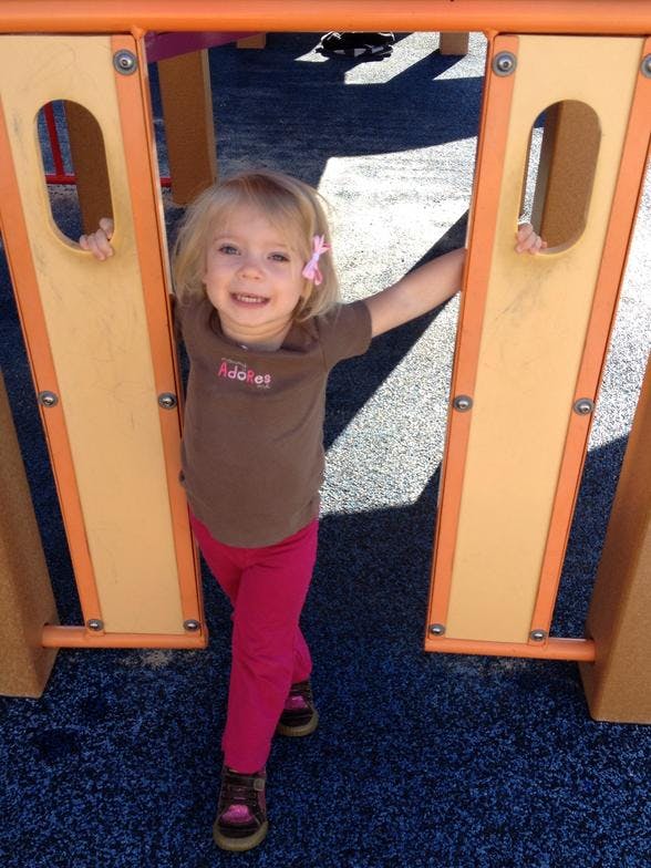 Child standing between two playground structures