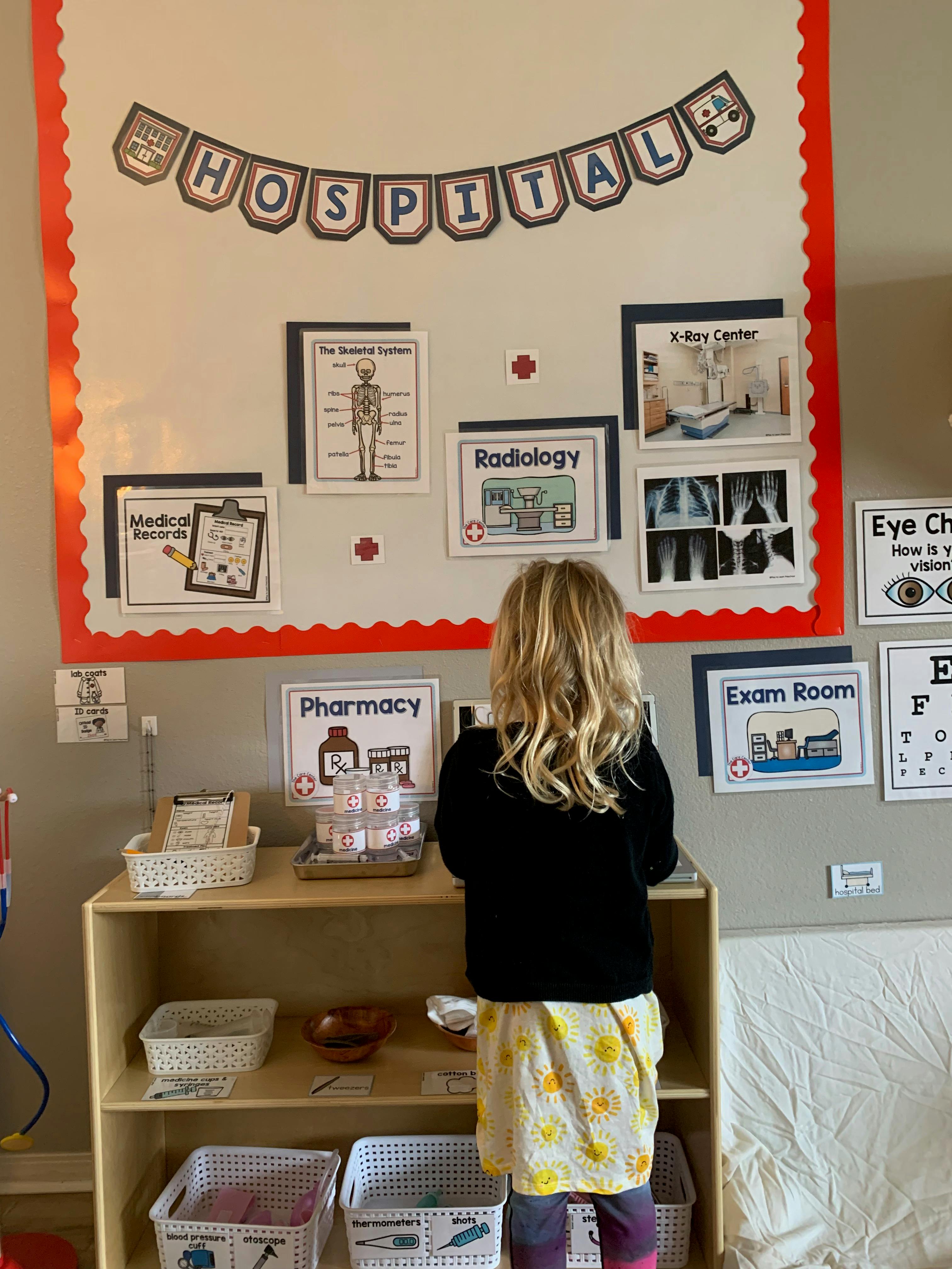 Child standing at a shelf in a classroom with hospital-themed decorations
