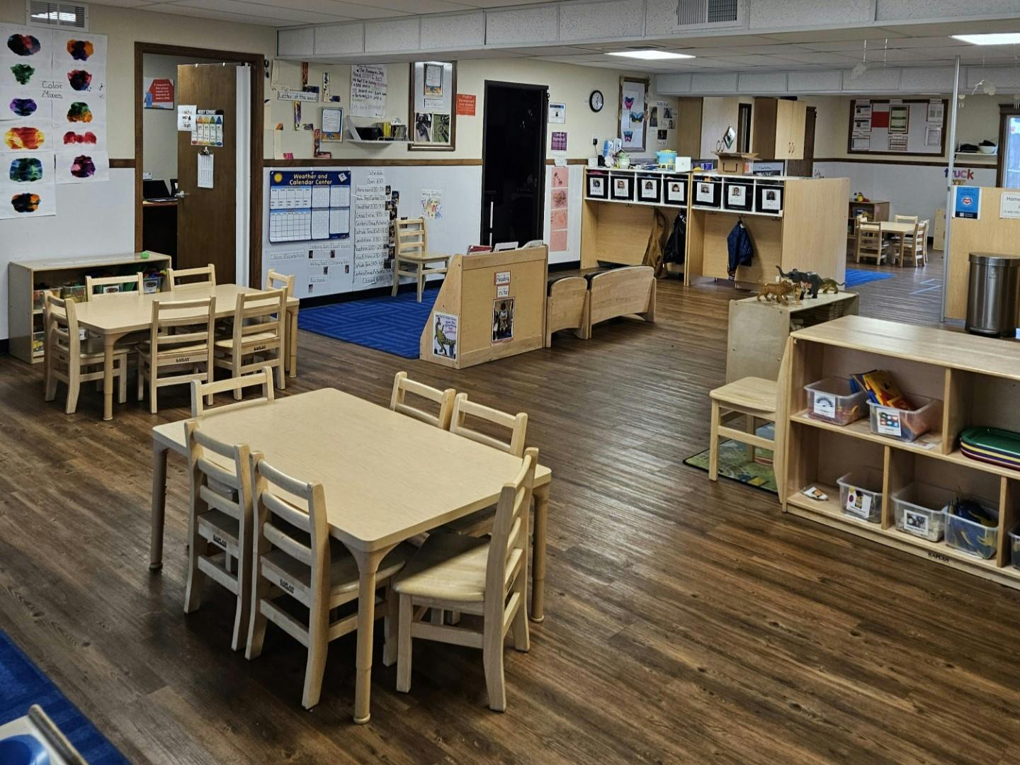 Classroom with multiple child-sized tables and chairs and storage shelves