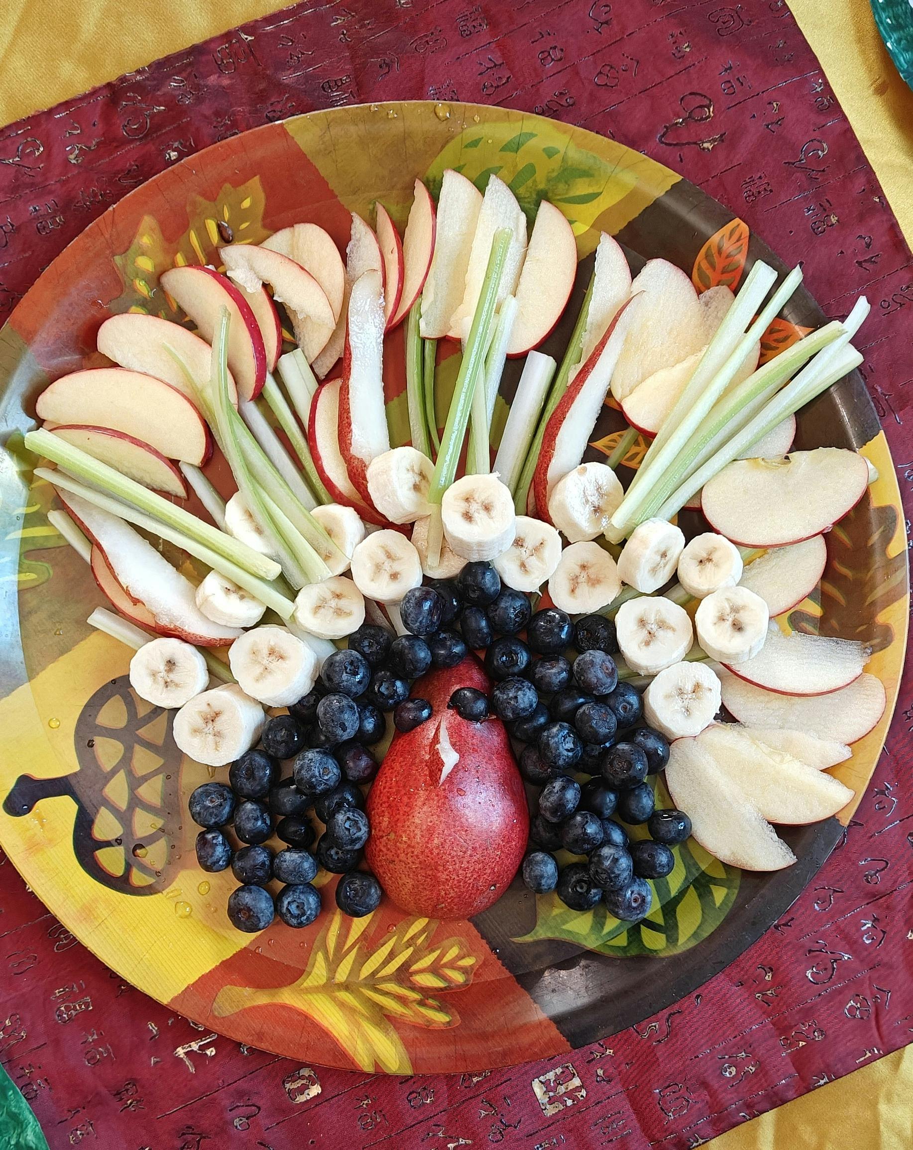 Fruit platter with apple slices, banana slices, blueberries, and a pear