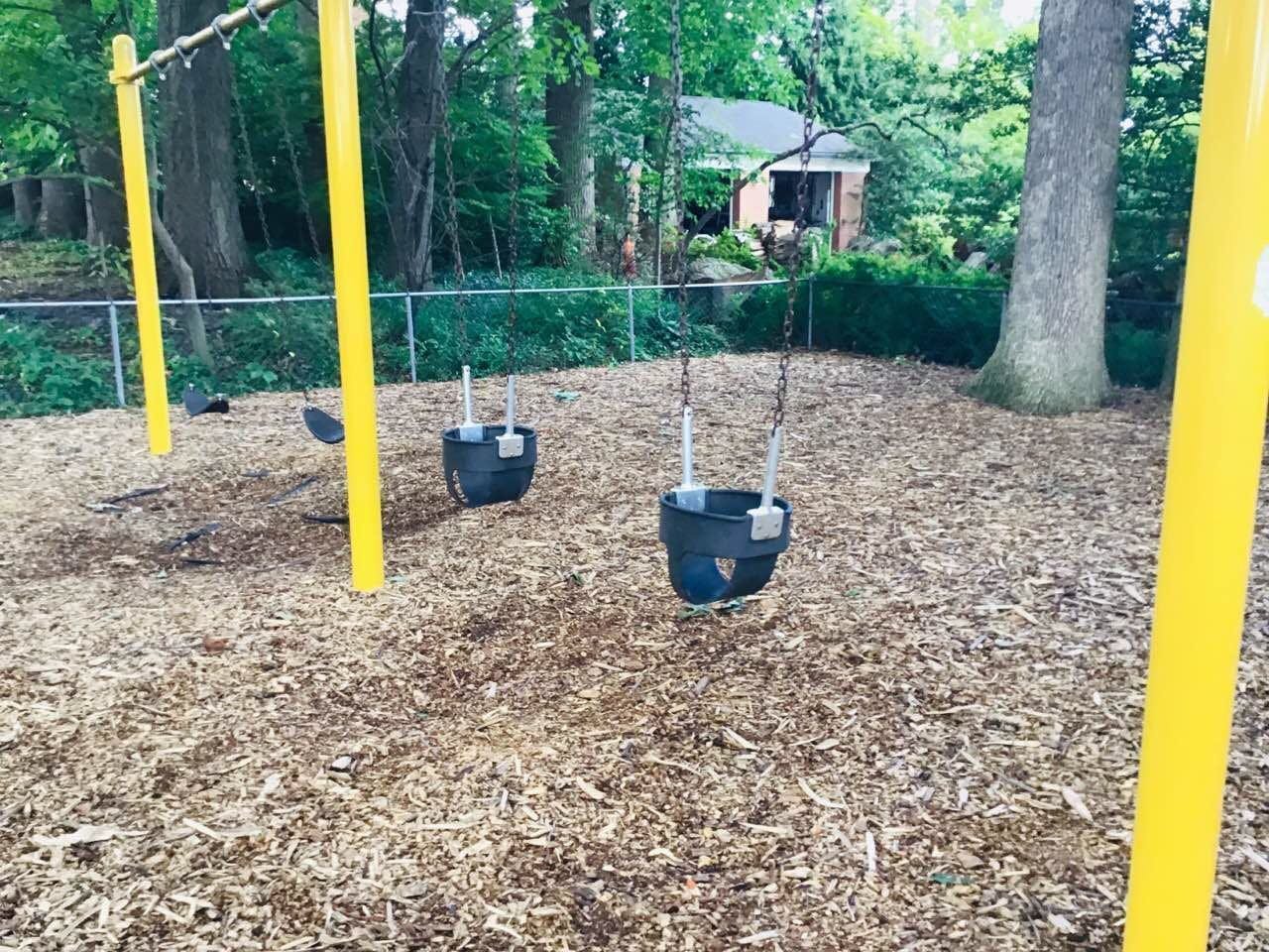 Empty swings on a playground with wood chips