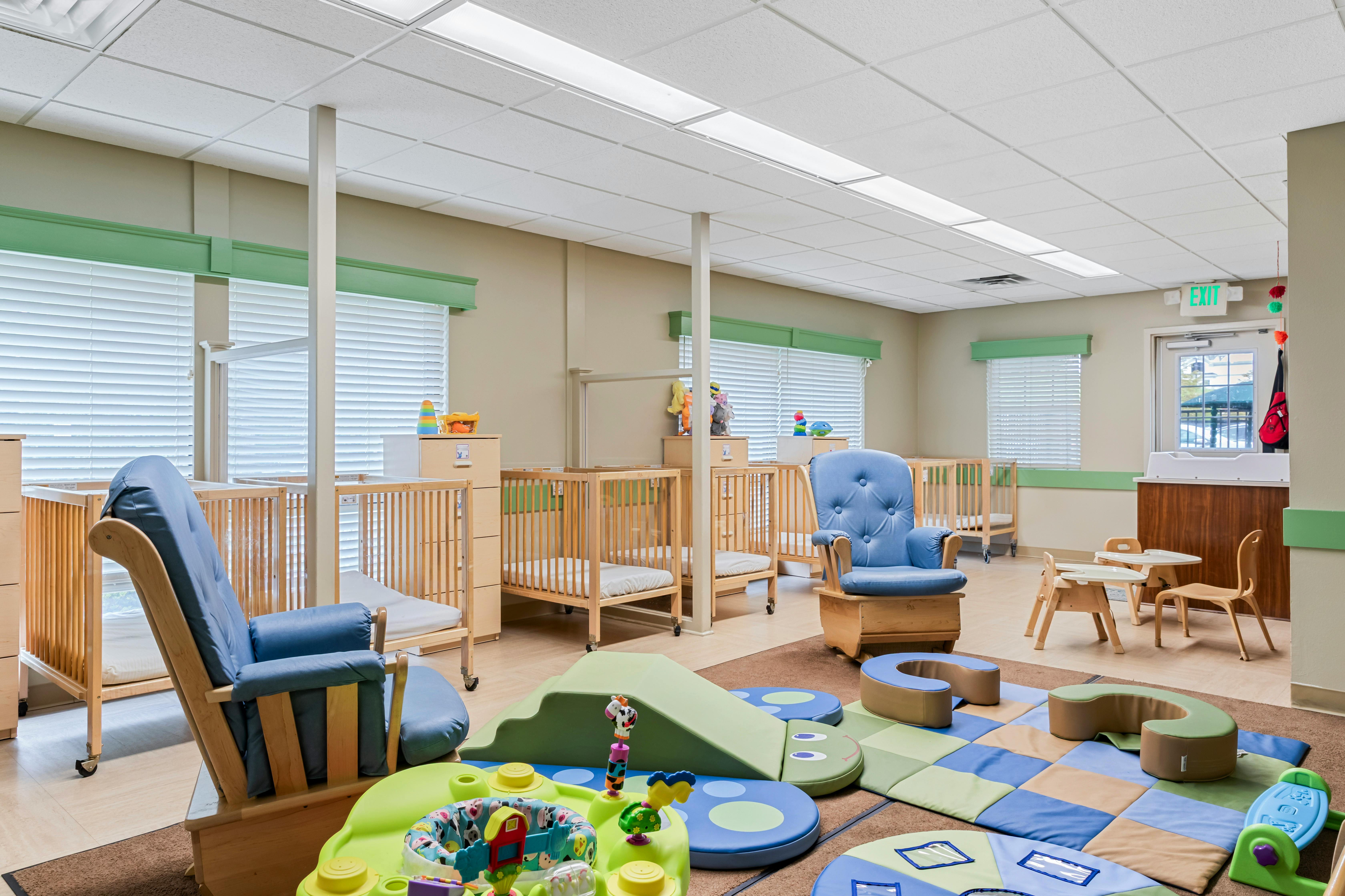Cribs, rocking chairs, and play mats in a bright nursery room