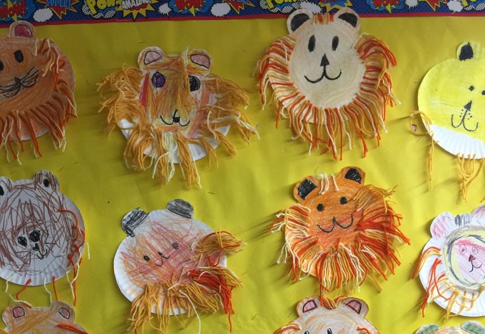 Paper plate lion crafts displayed on a yellow background