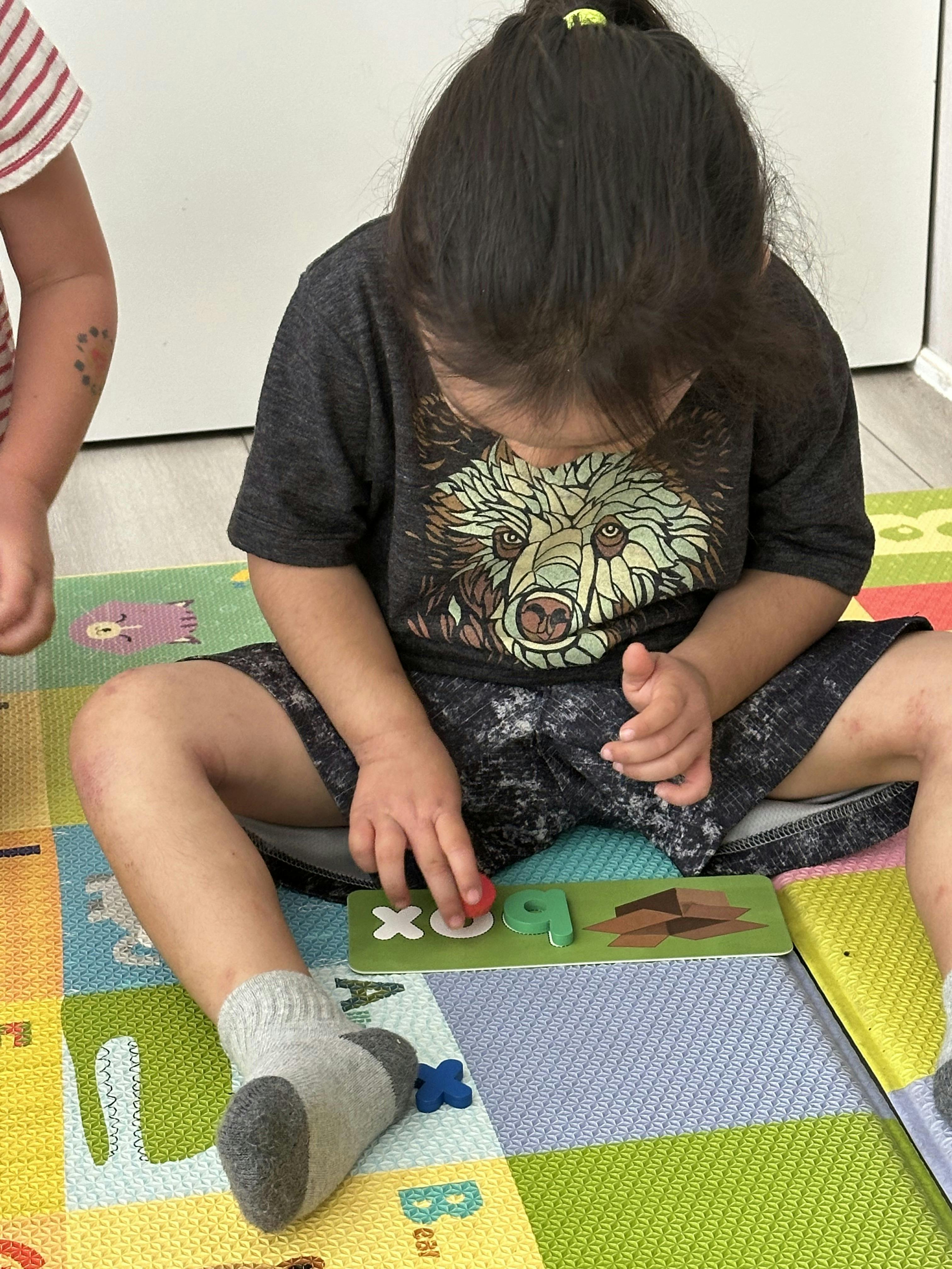 Child on a colorful mat playing with letter puzzles