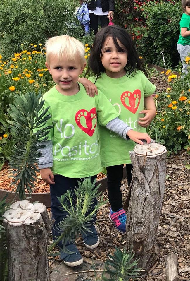 Two children in matching green shirts with red heart logos standing outdoors