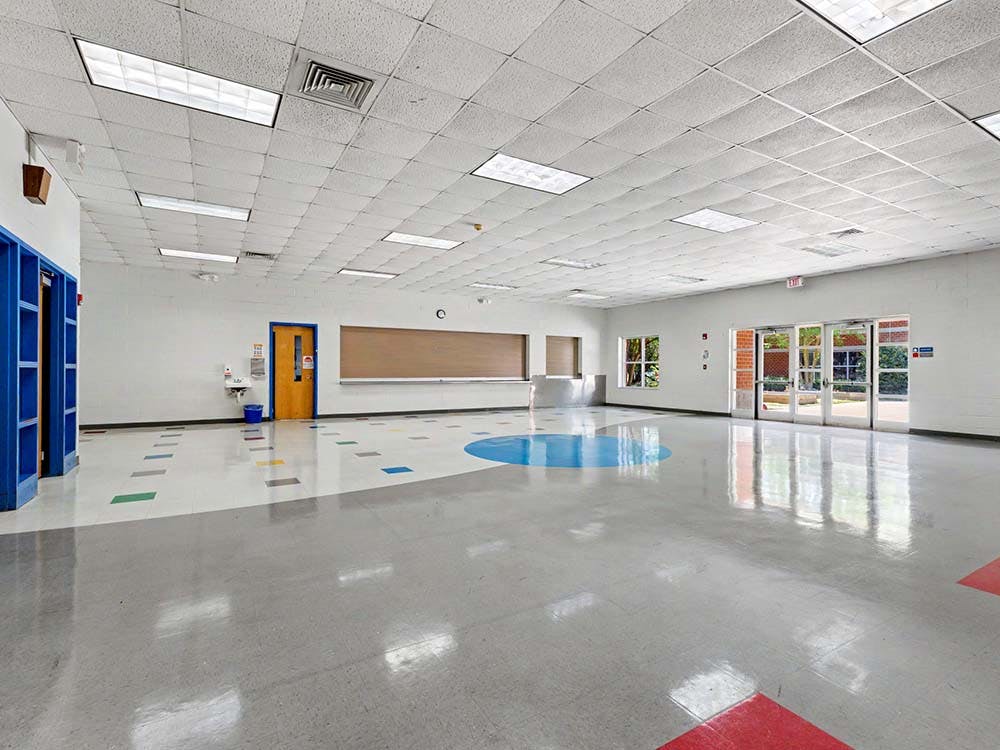 Empty school hallway with blue lockers and colorful floor patterns
