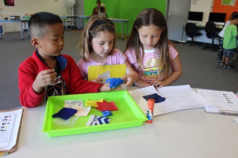 Three children at a table with craft supplies