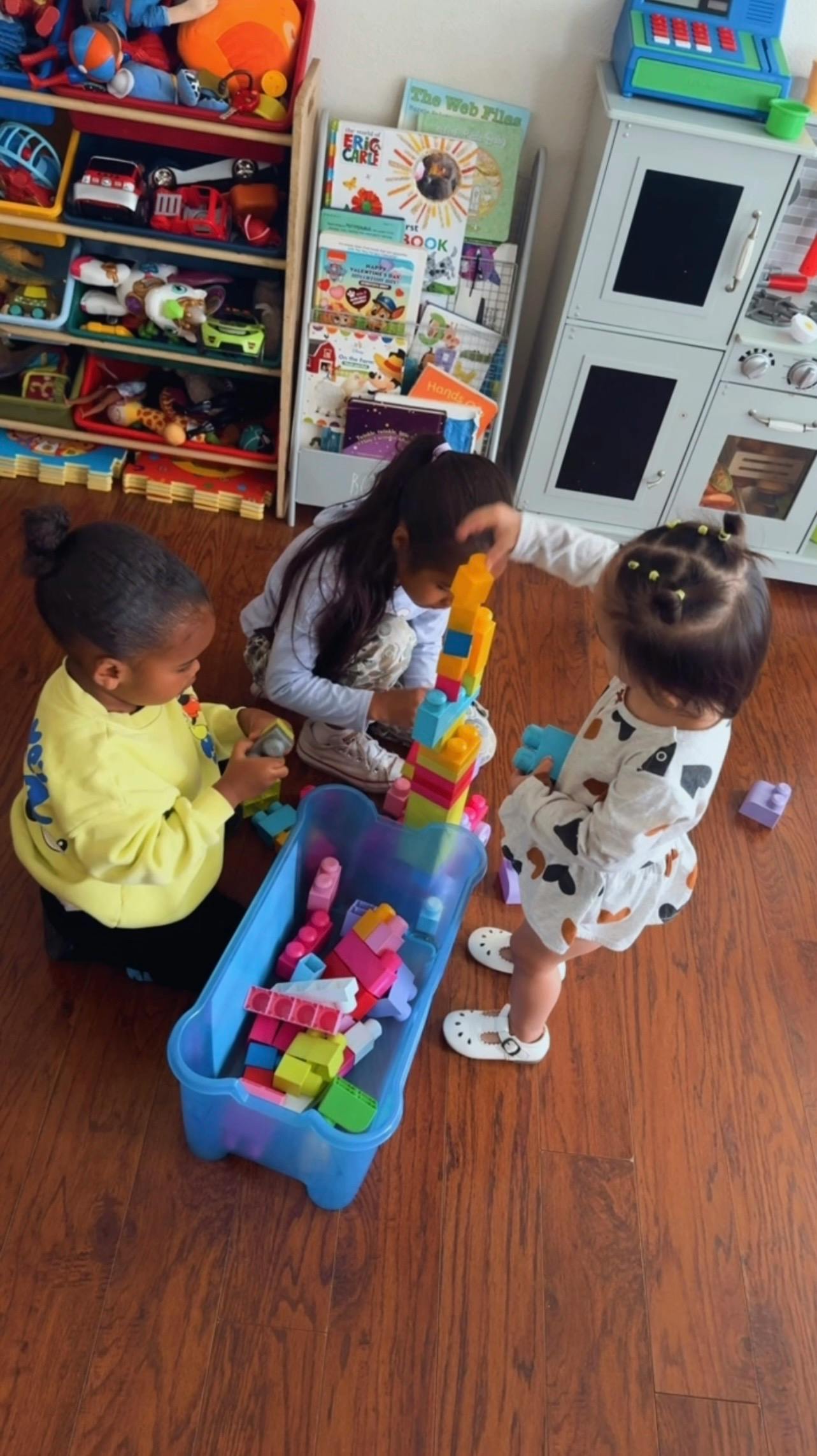 Three children playing with colorful plastic building blocks