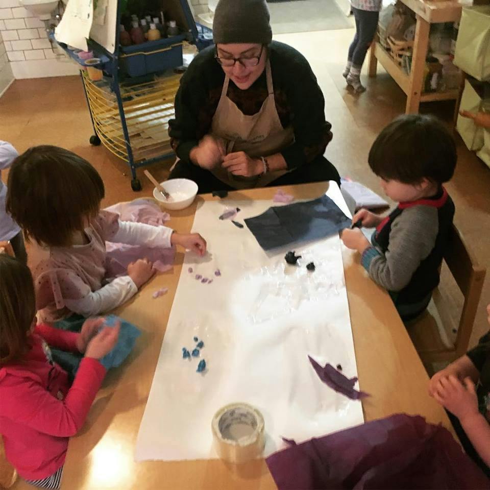 Person and three children doing an art activity at a table