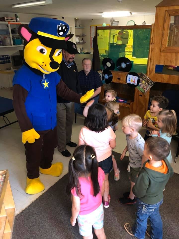 Person in dog mascot costume interacting with children