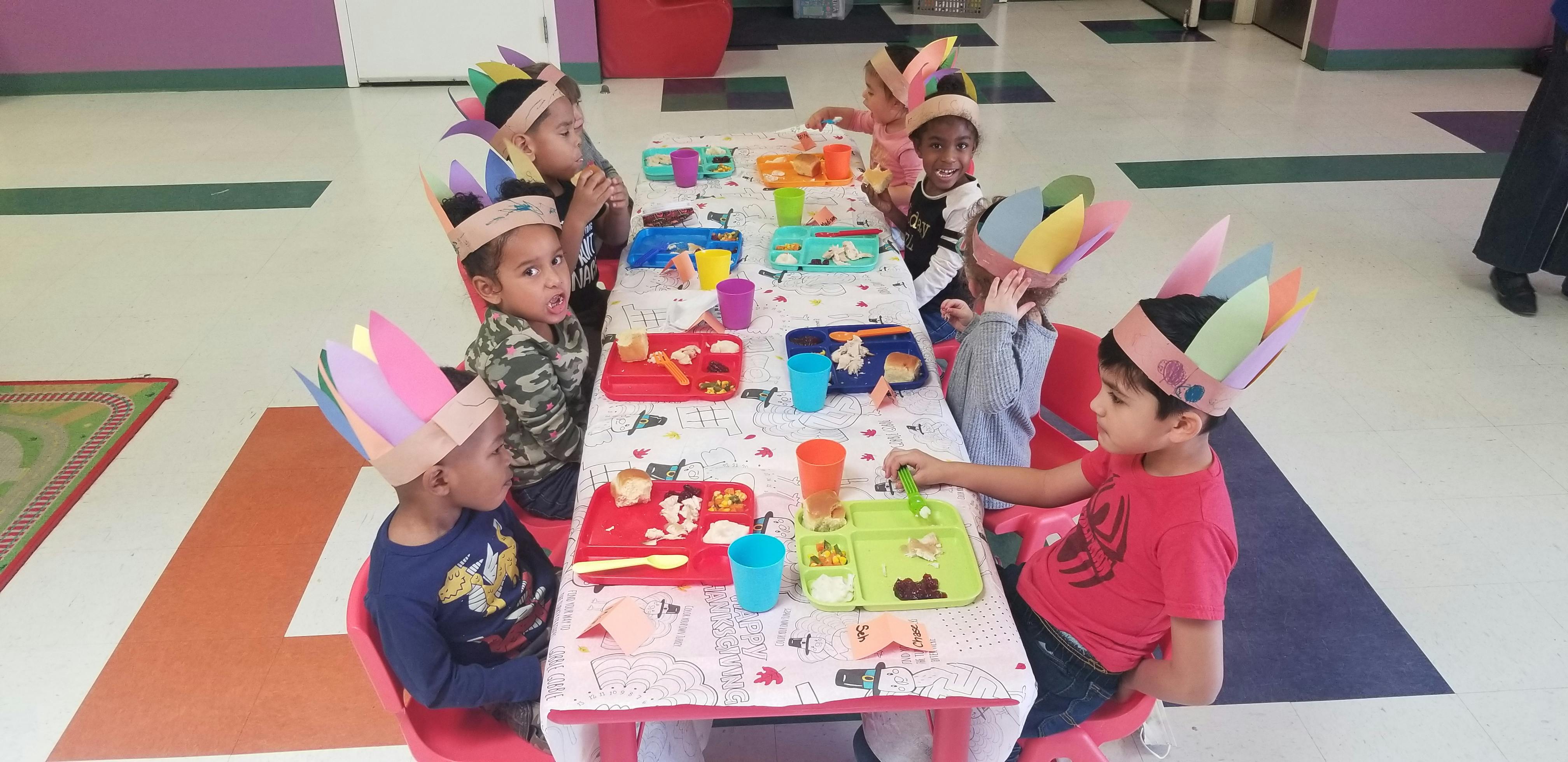 Children wearing paper feather headbands sitting at a table
