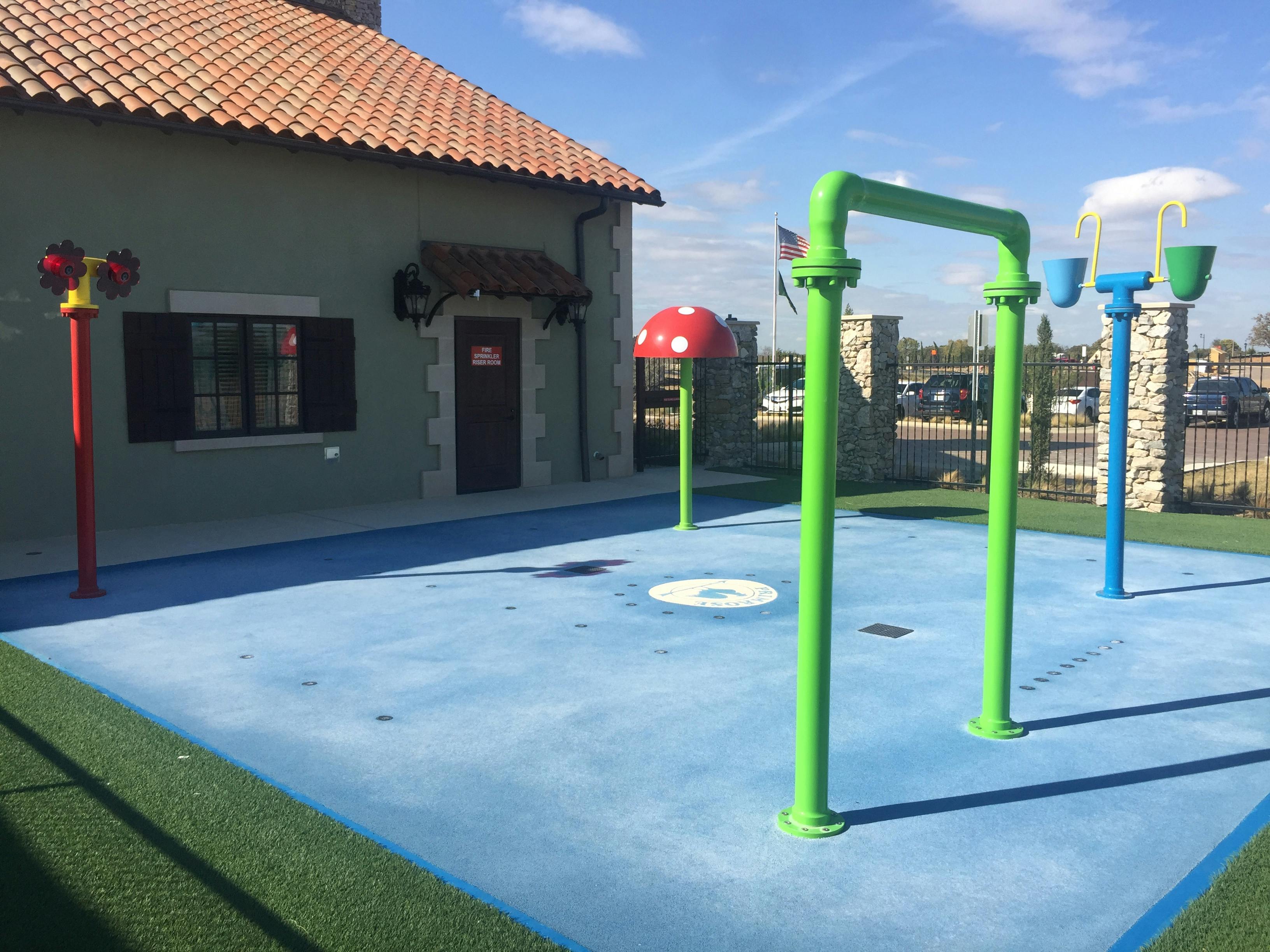 Outdoor splash pad with water features next to a building