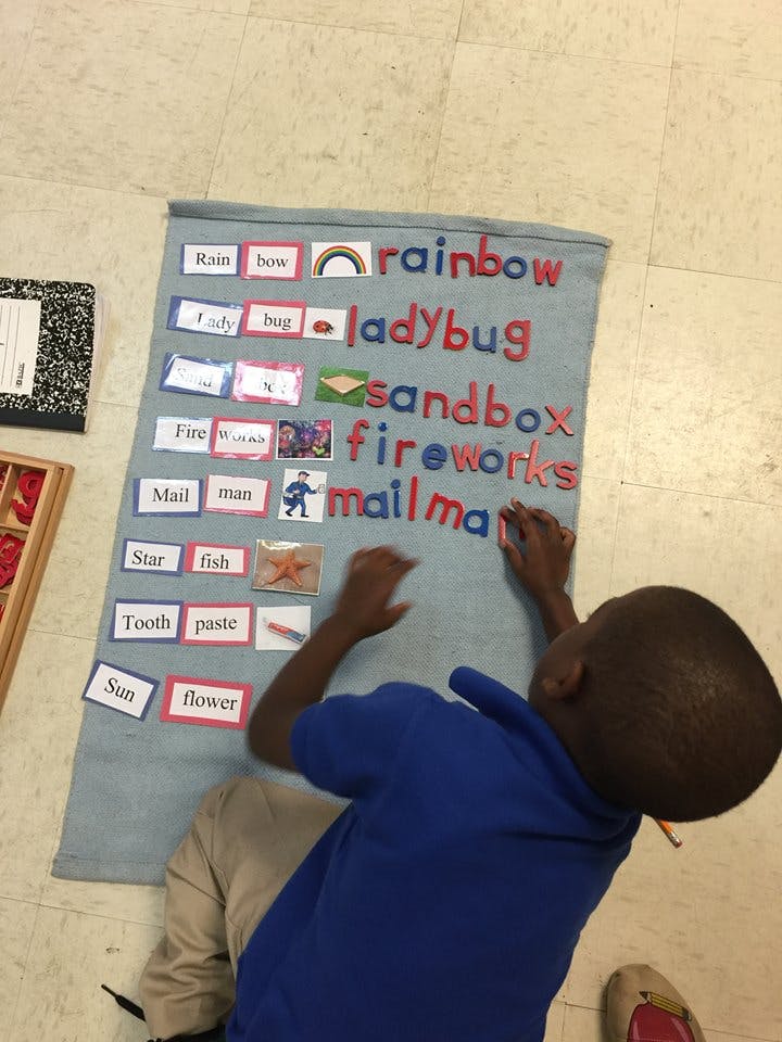 Child on floor arranging word and picture cards on a blue mat