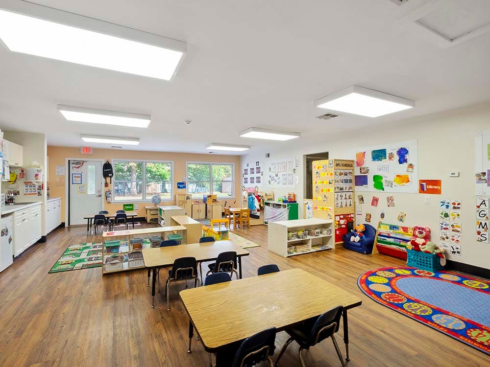 Empty colorful preschool classroom with small tables and chairs