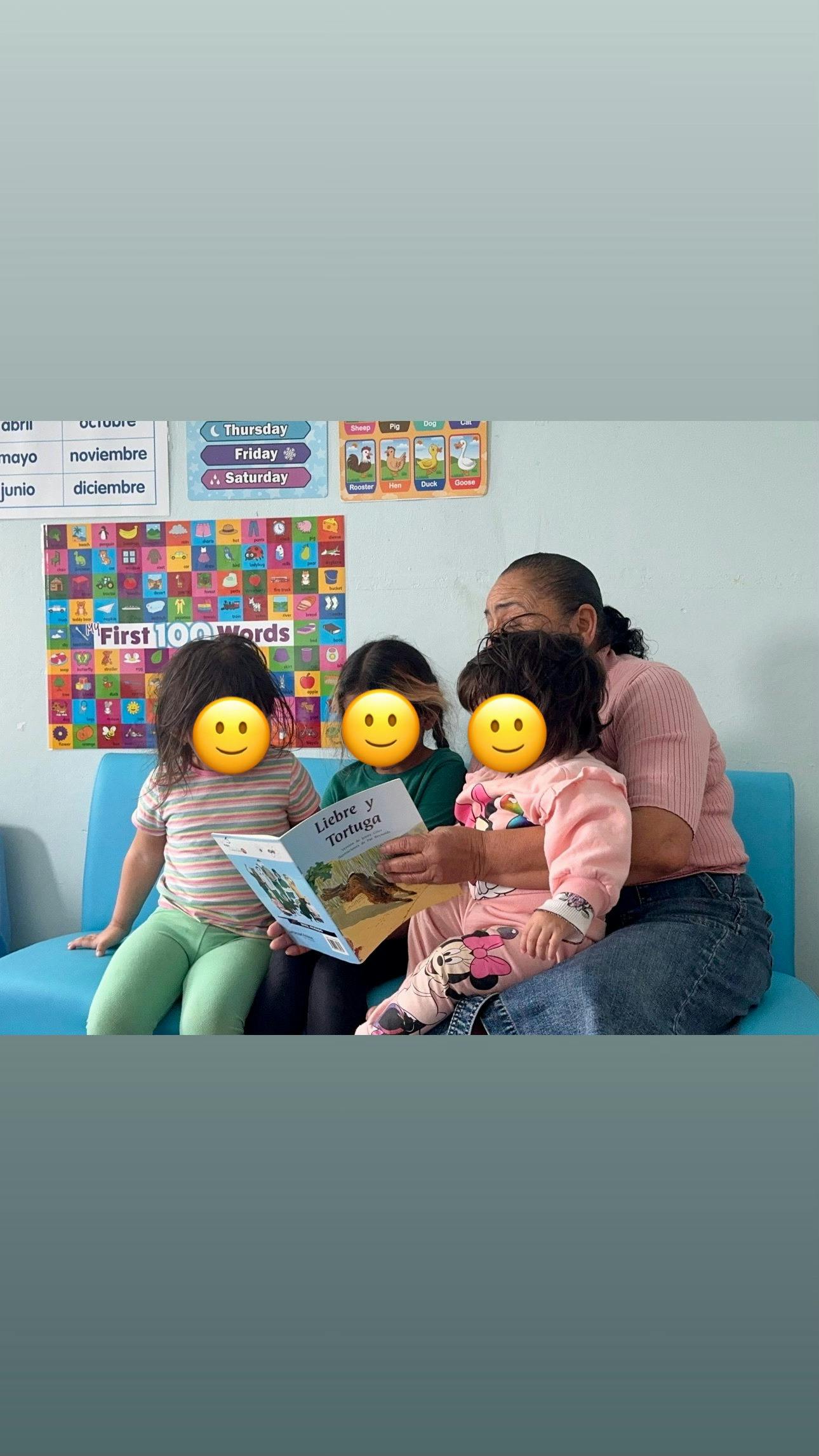 Adult reading a book to three children