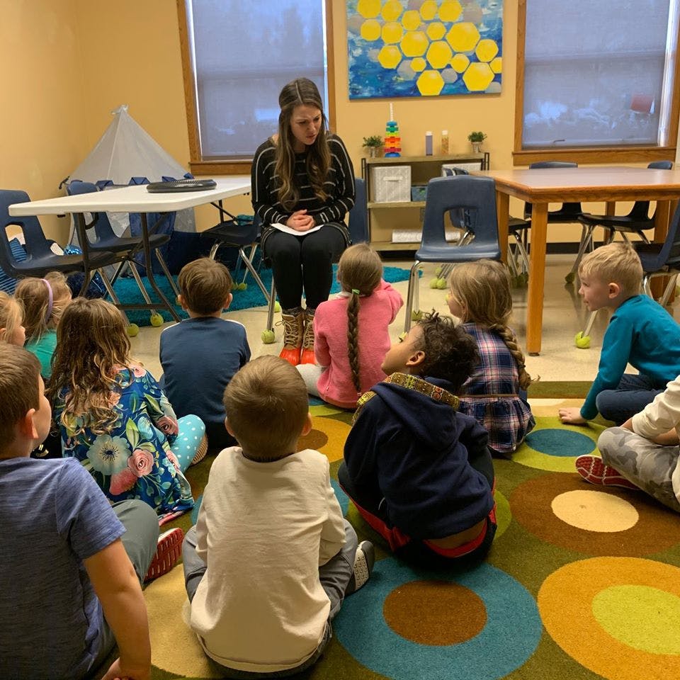 Person reading to a group of children in a classroom