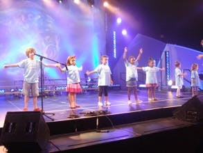 Children on a stage with arms outstretched