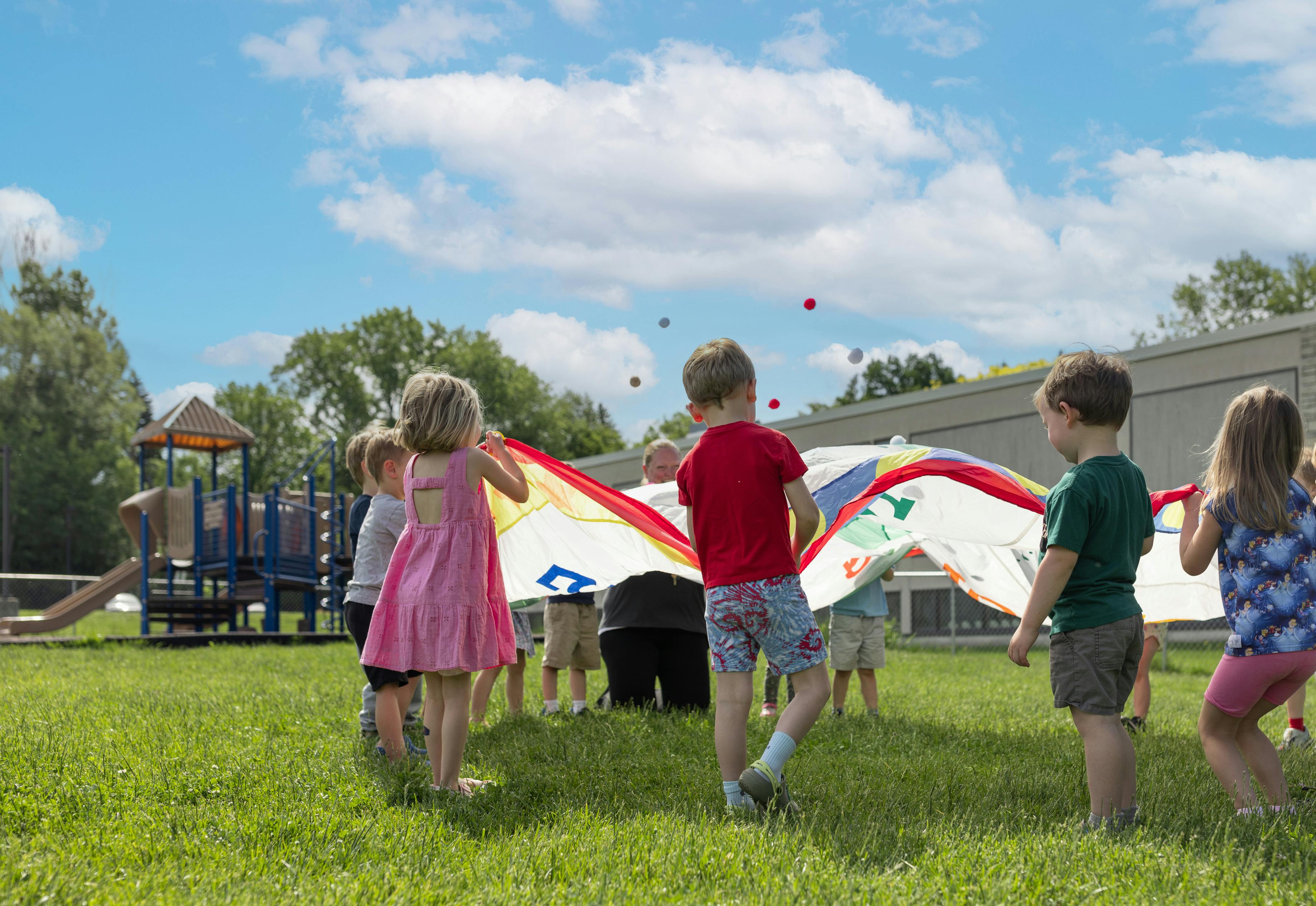 Children playing with a colorful parachute on a grassy field