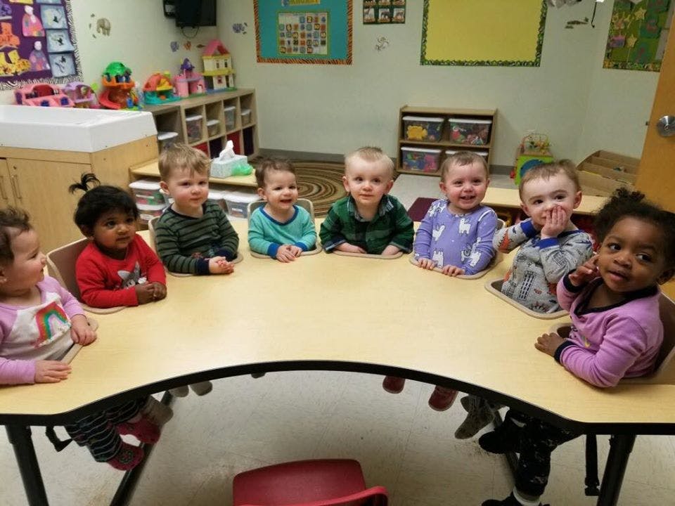 Seven children sitting around a table in a classroom