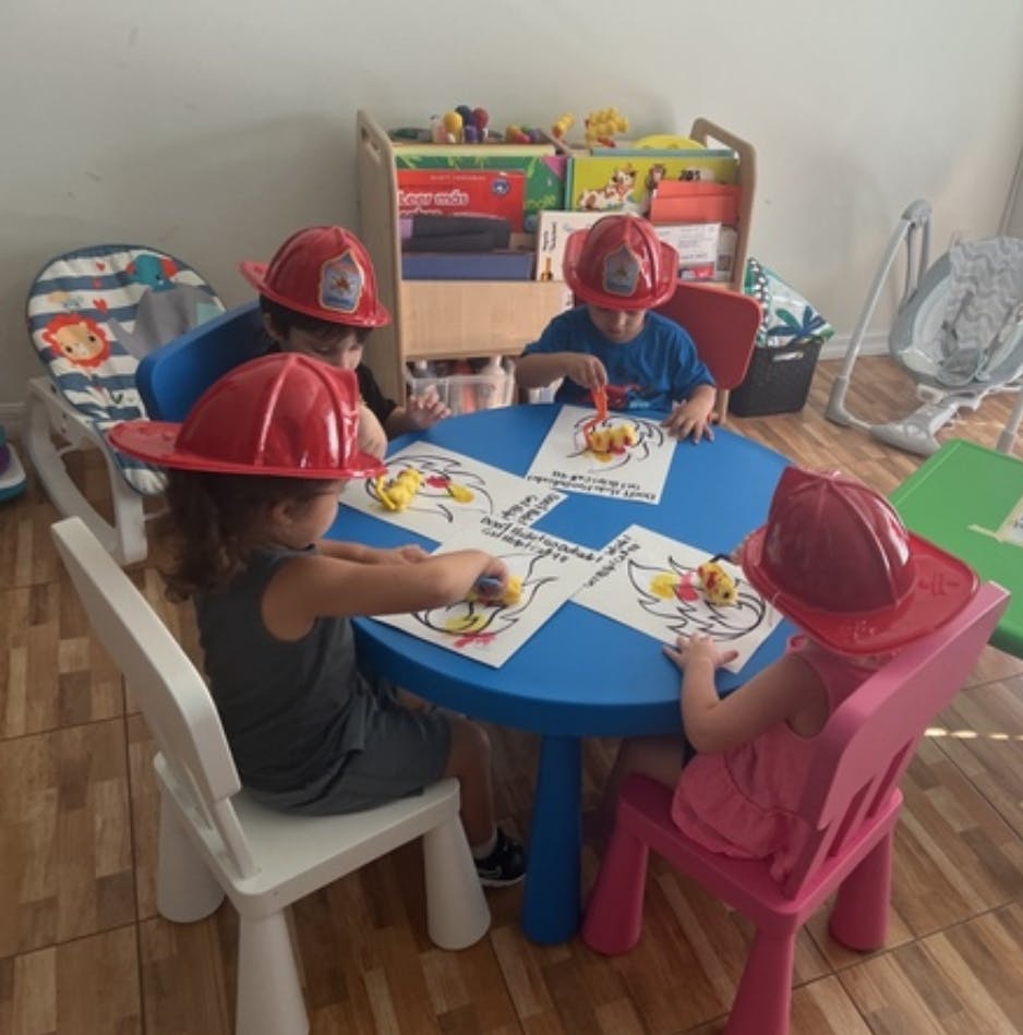 Children wearing red hats coloring at a blue table