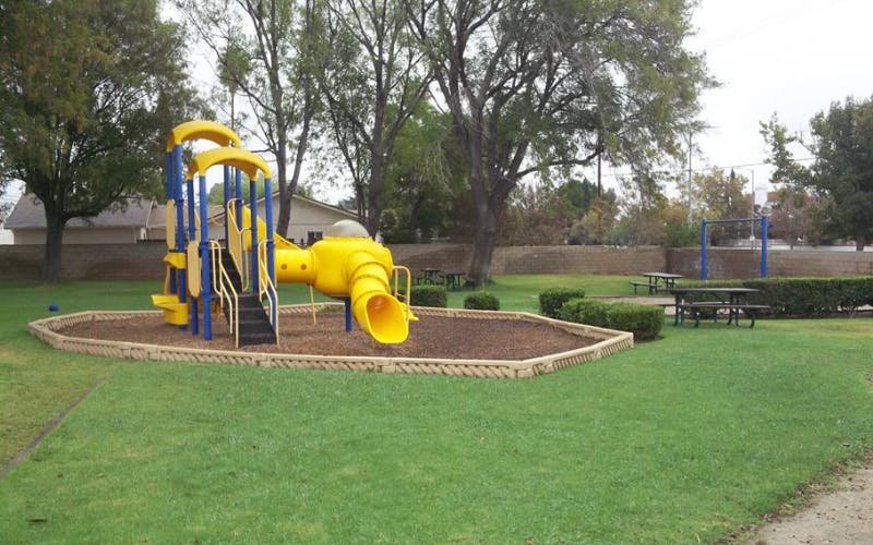 Playground with yellow and blue climbing structure and slides on wood chips