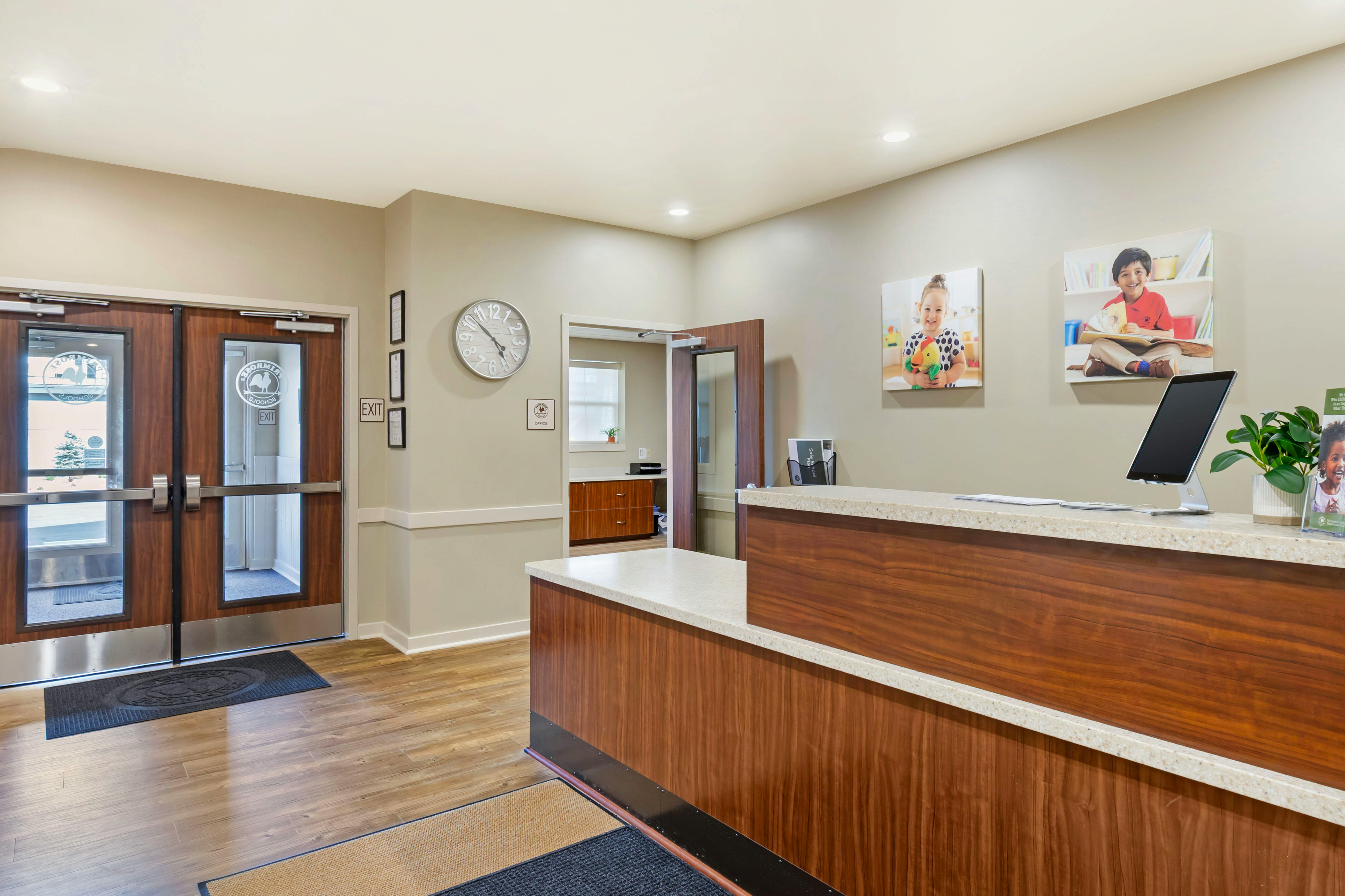 An office lobby with a reception desk, a large clock, and two sets of double doors
