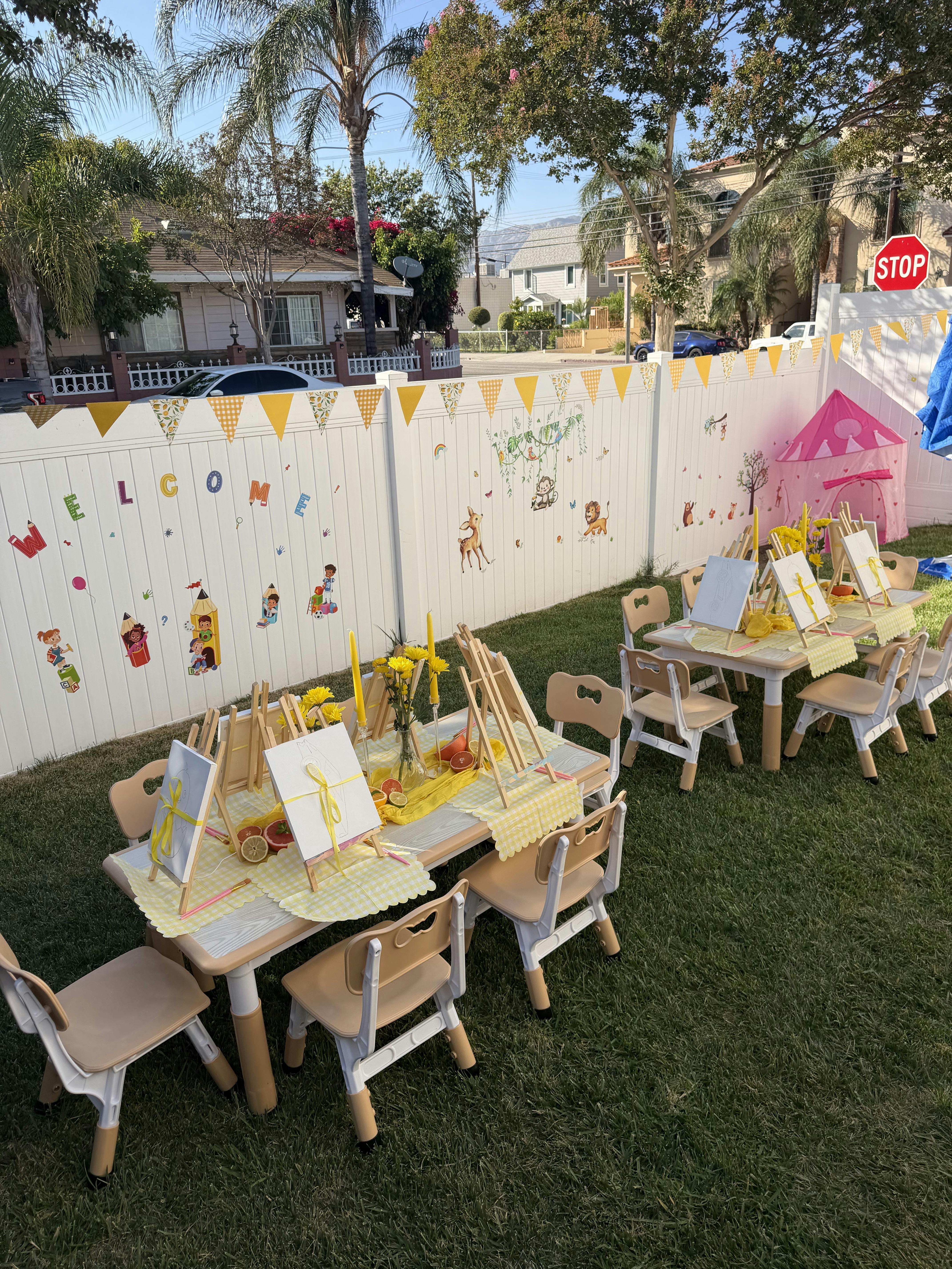 Small tables and chairs set up for a children painting activity outdoors