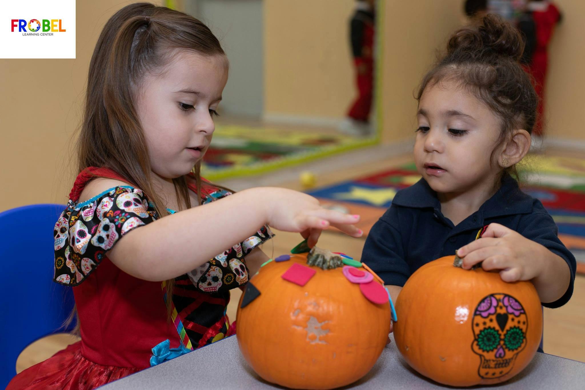 Two children decorating pumpkins