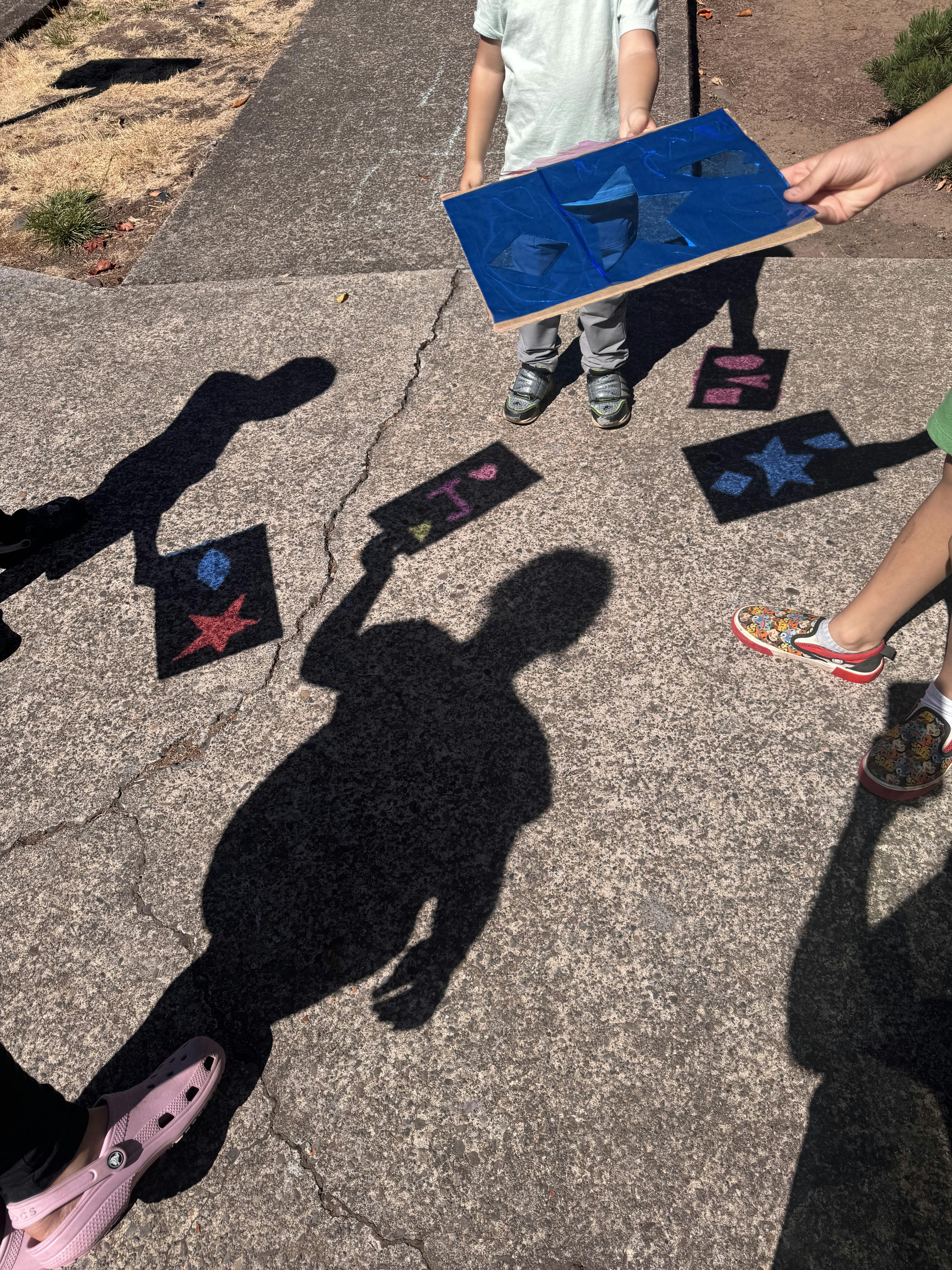 People holding sun print paper with shadows on the ground