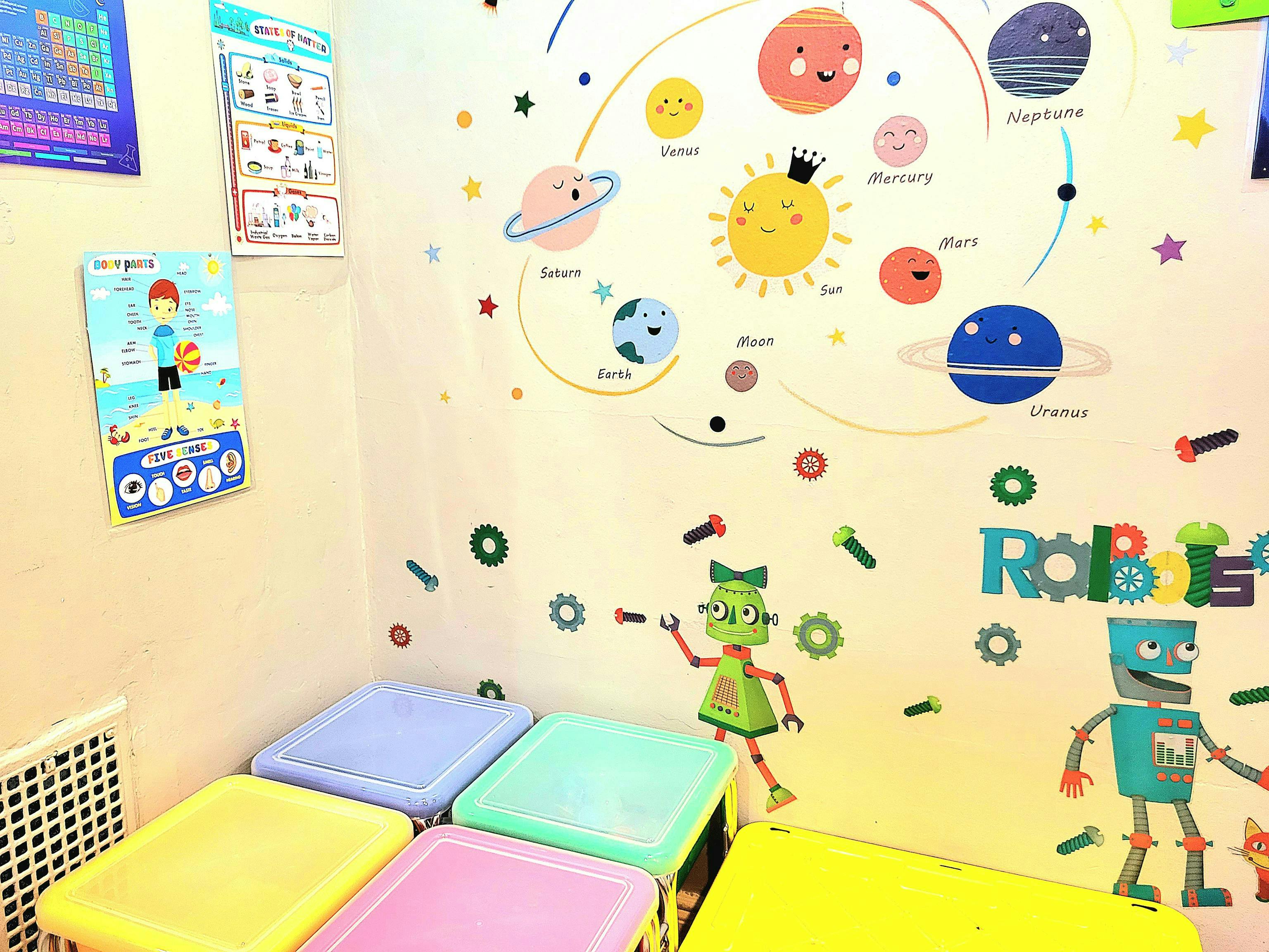 Classroom with colorful tables and wall decals of planets and robots
