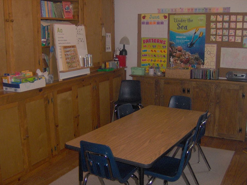 Classroom with a table and chairs, bulletin boards, and wooden cabinets