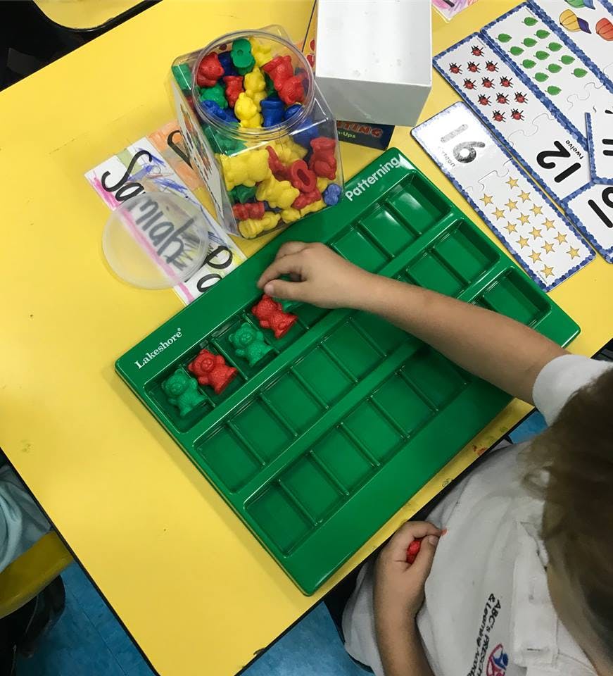 Child placing bear counters into a green patterning tray